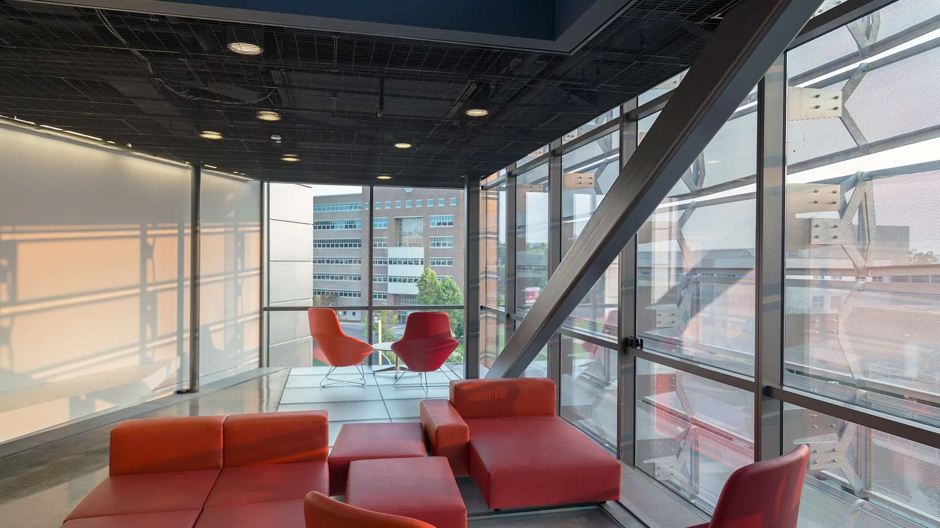 Red lounge chairs behind a steel and glass wall