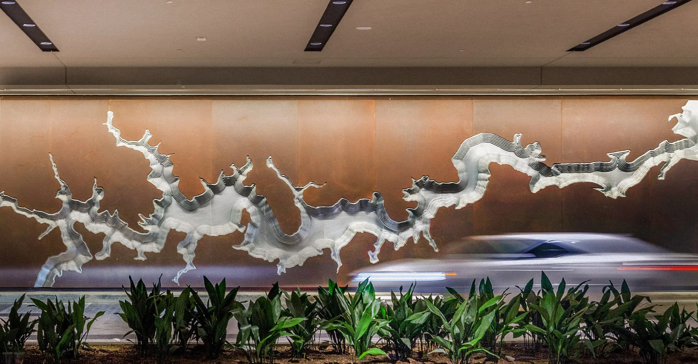 A metal river sculpture above a planted bed