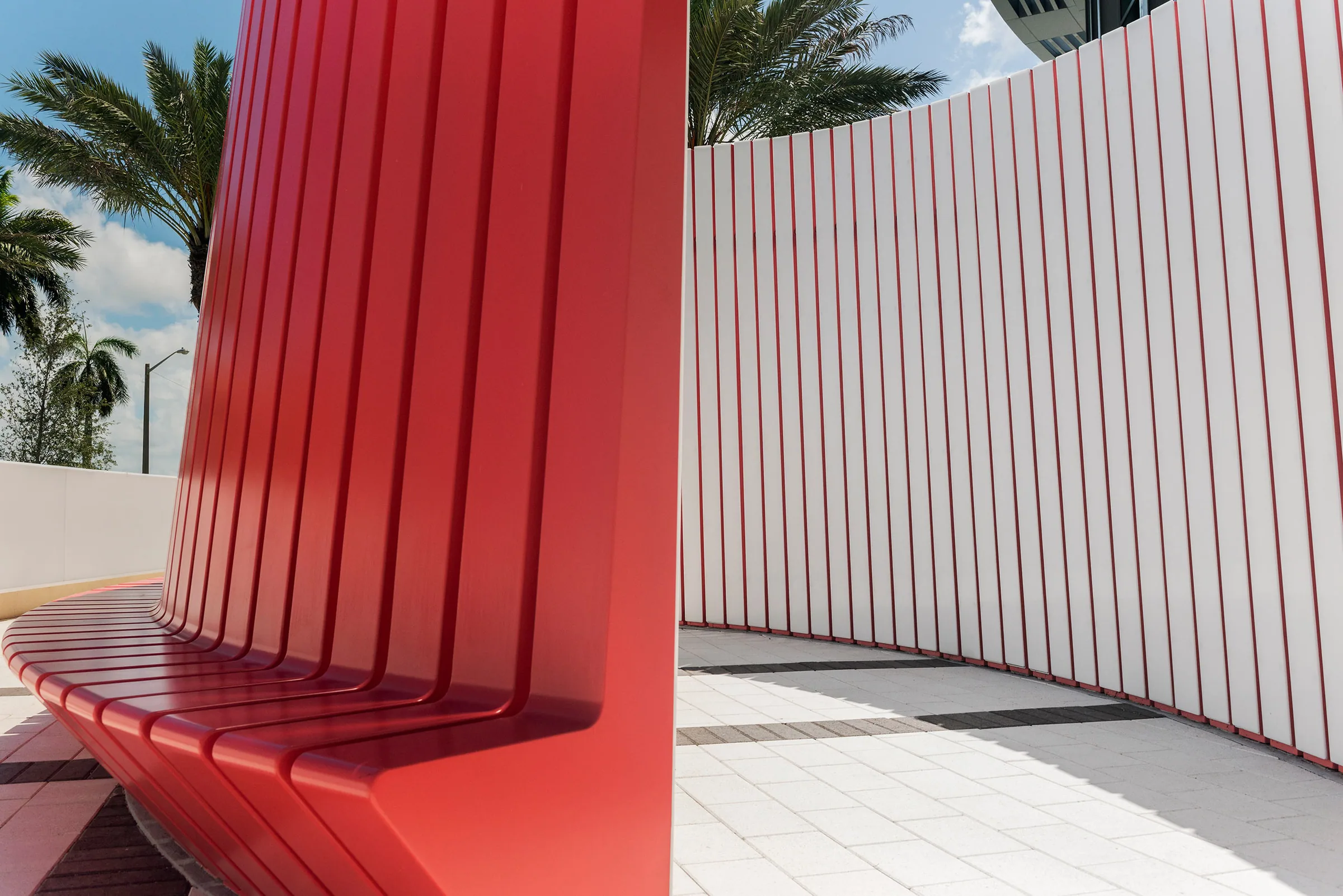 A sculptural red bench against a white rib wall
