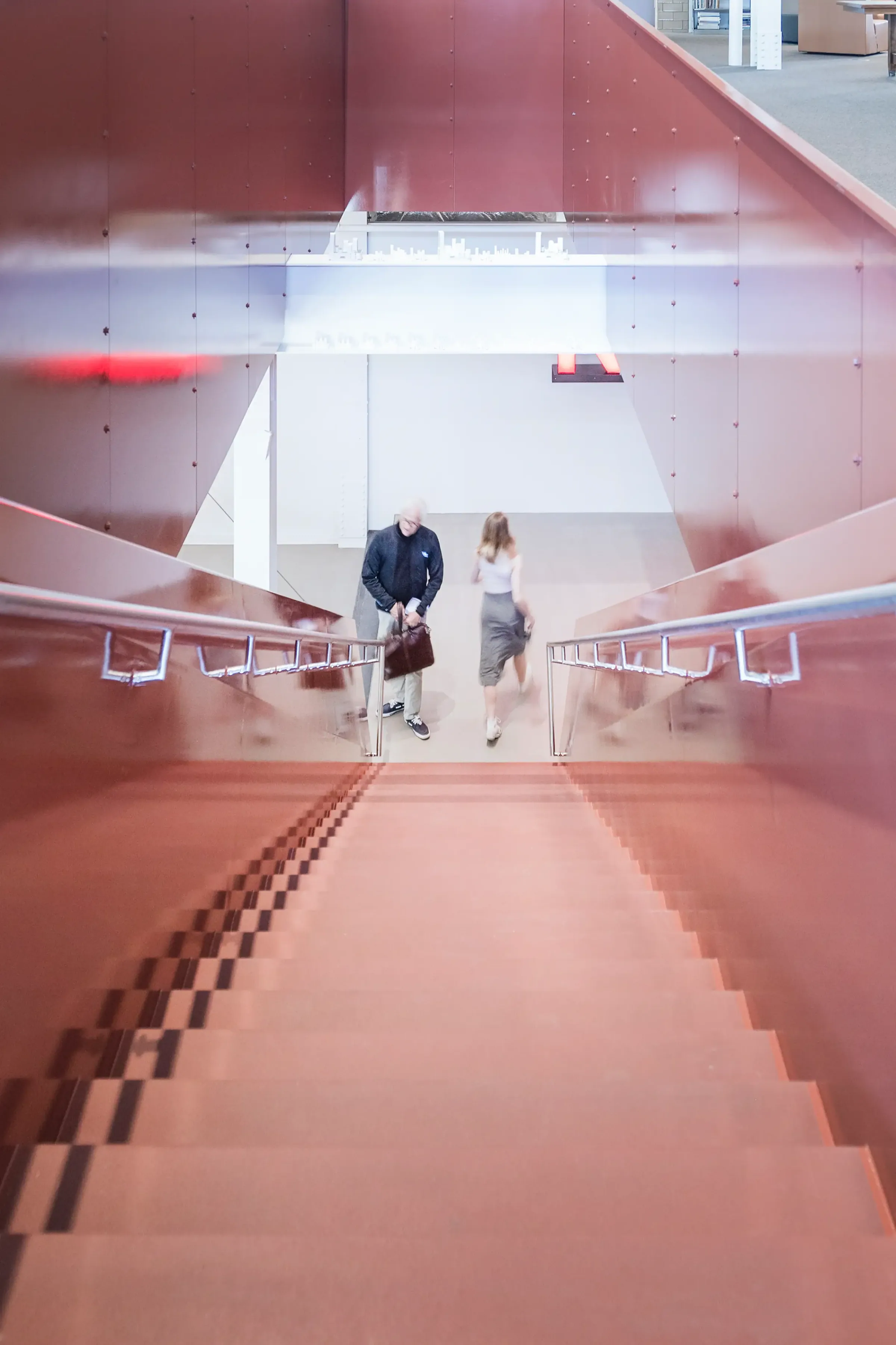 A red stair rising through a gallery