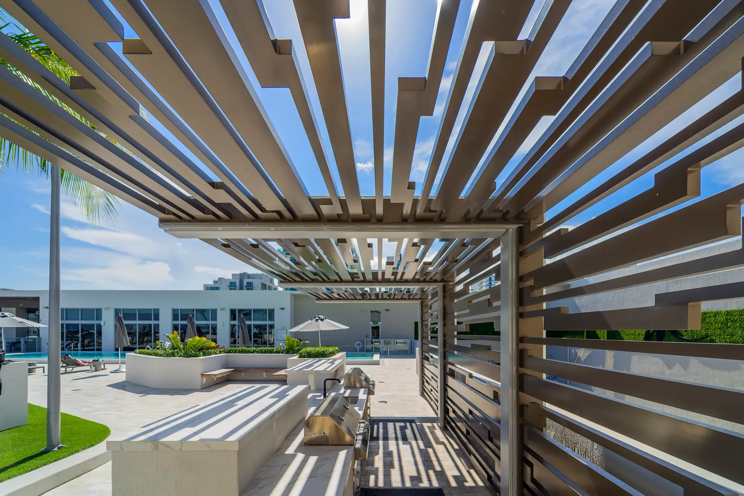A pergola of slatted fins over a pool deck