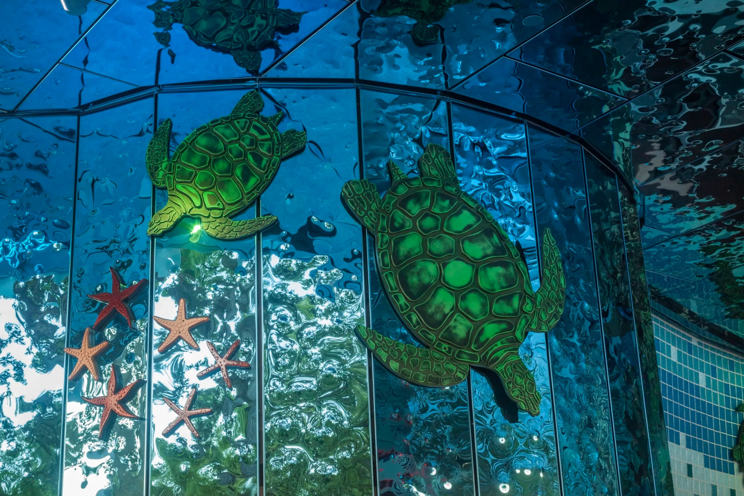 Glass sea turtles in a blue tiled wall