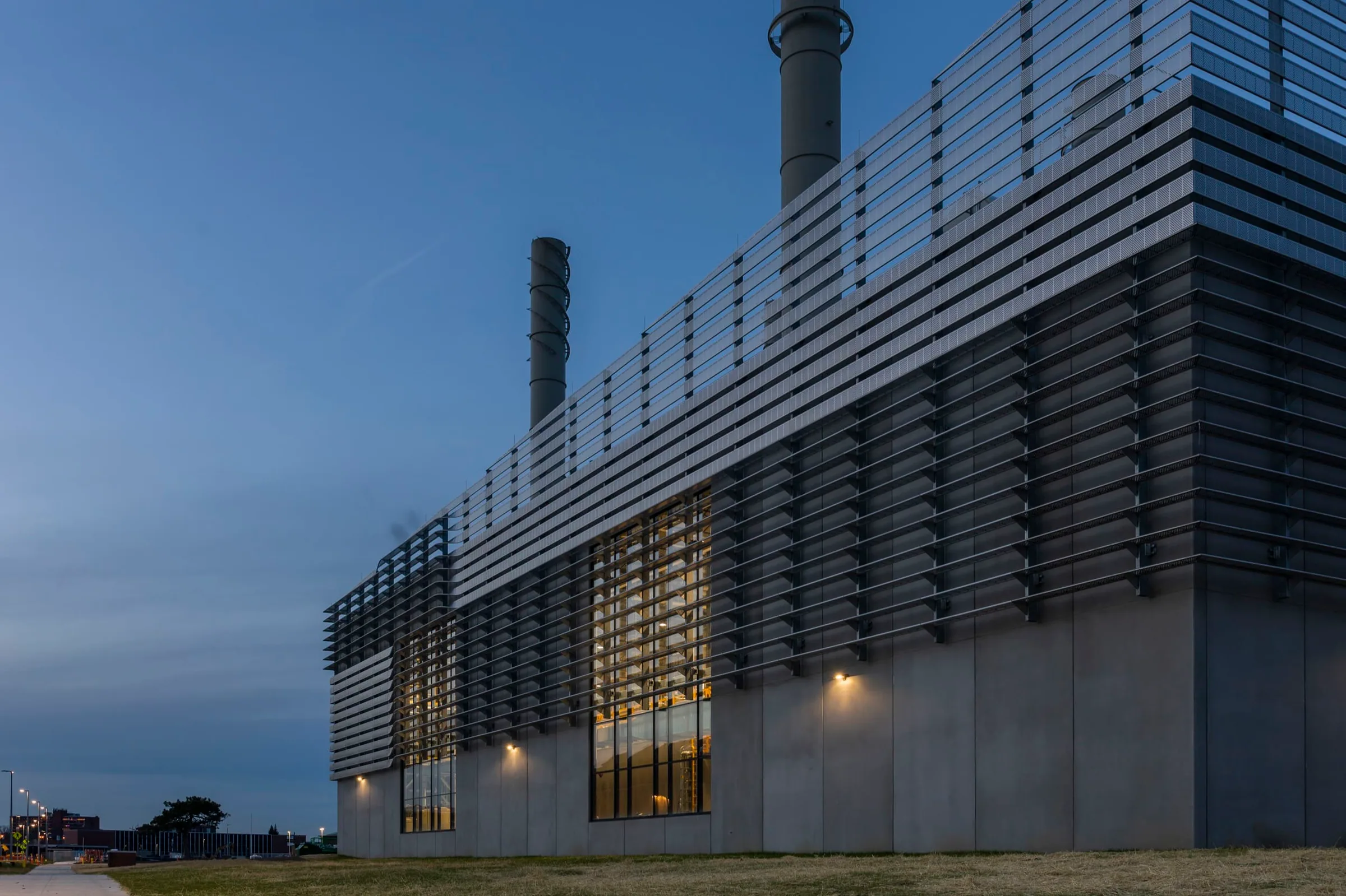The plant’s finned corner and smokestacks at blue hour