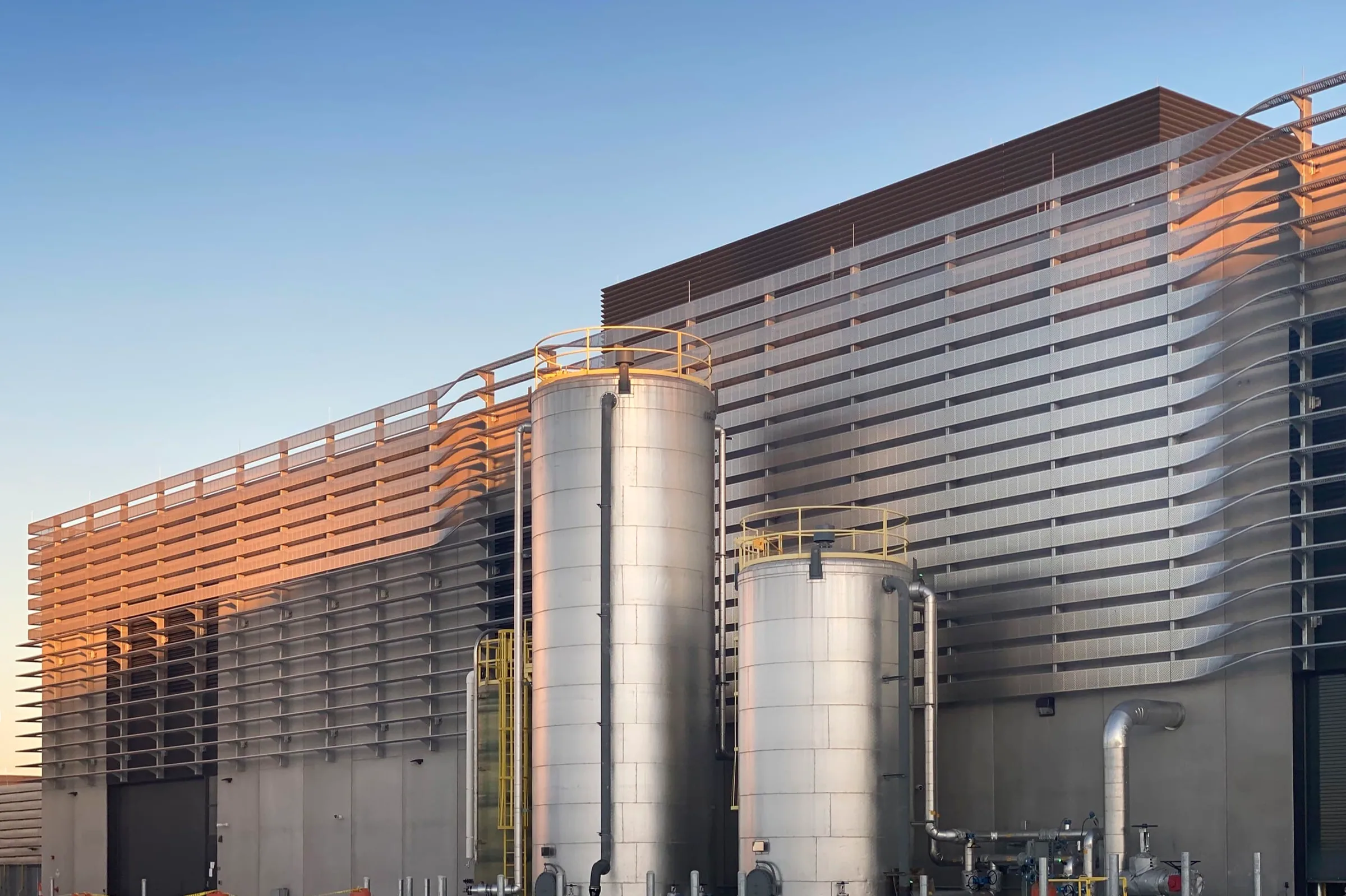 Stainless tanks in front of the finned façade in low sun