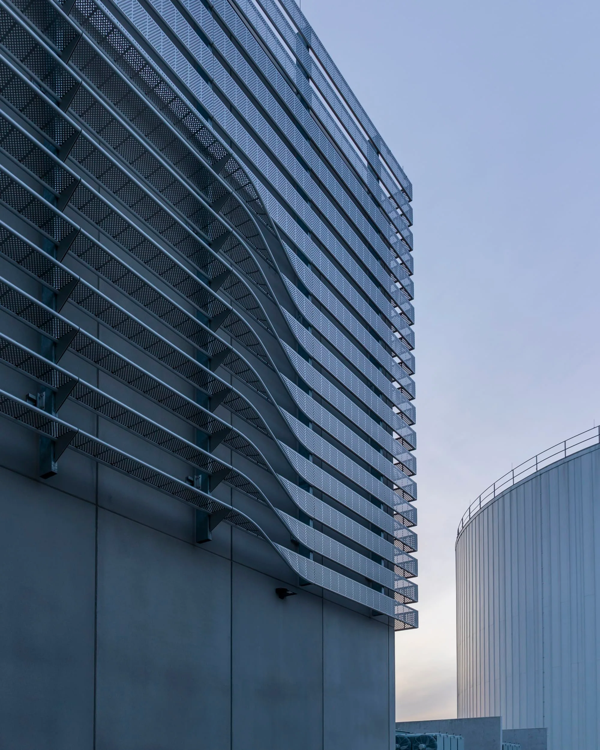 The fins curving around the building’s corner beside a tank