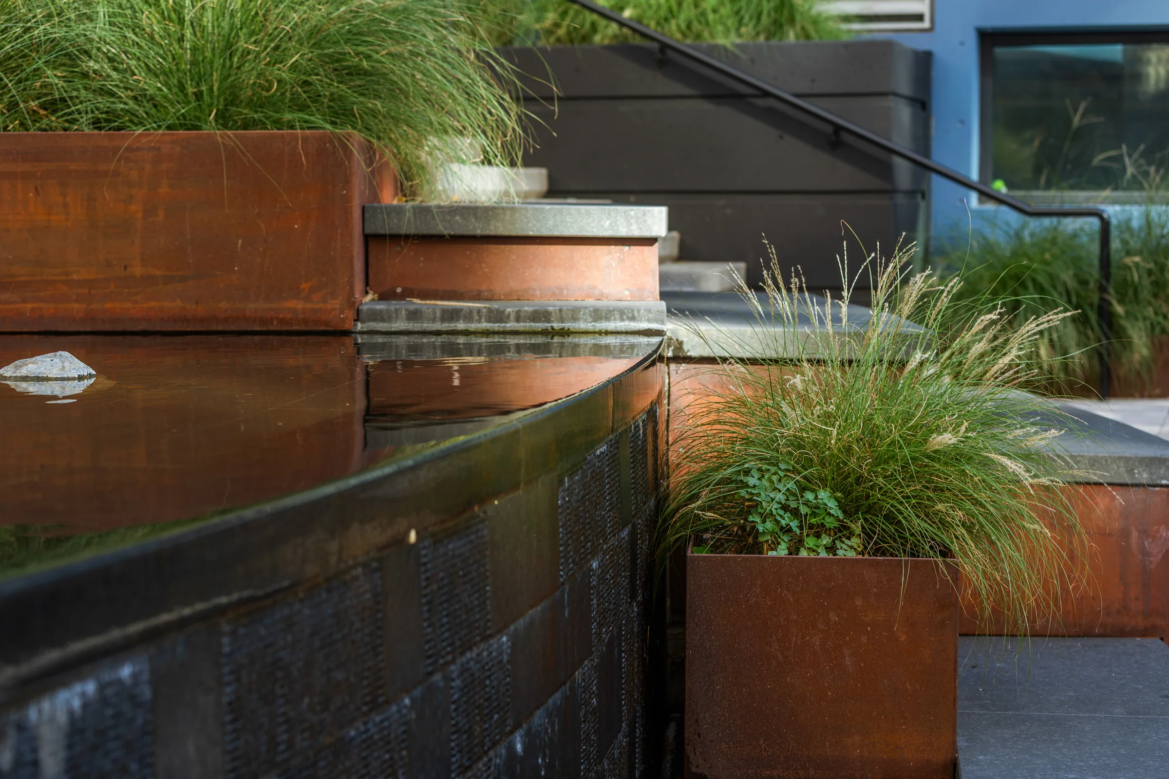A steel planter above a black granite fountain wall