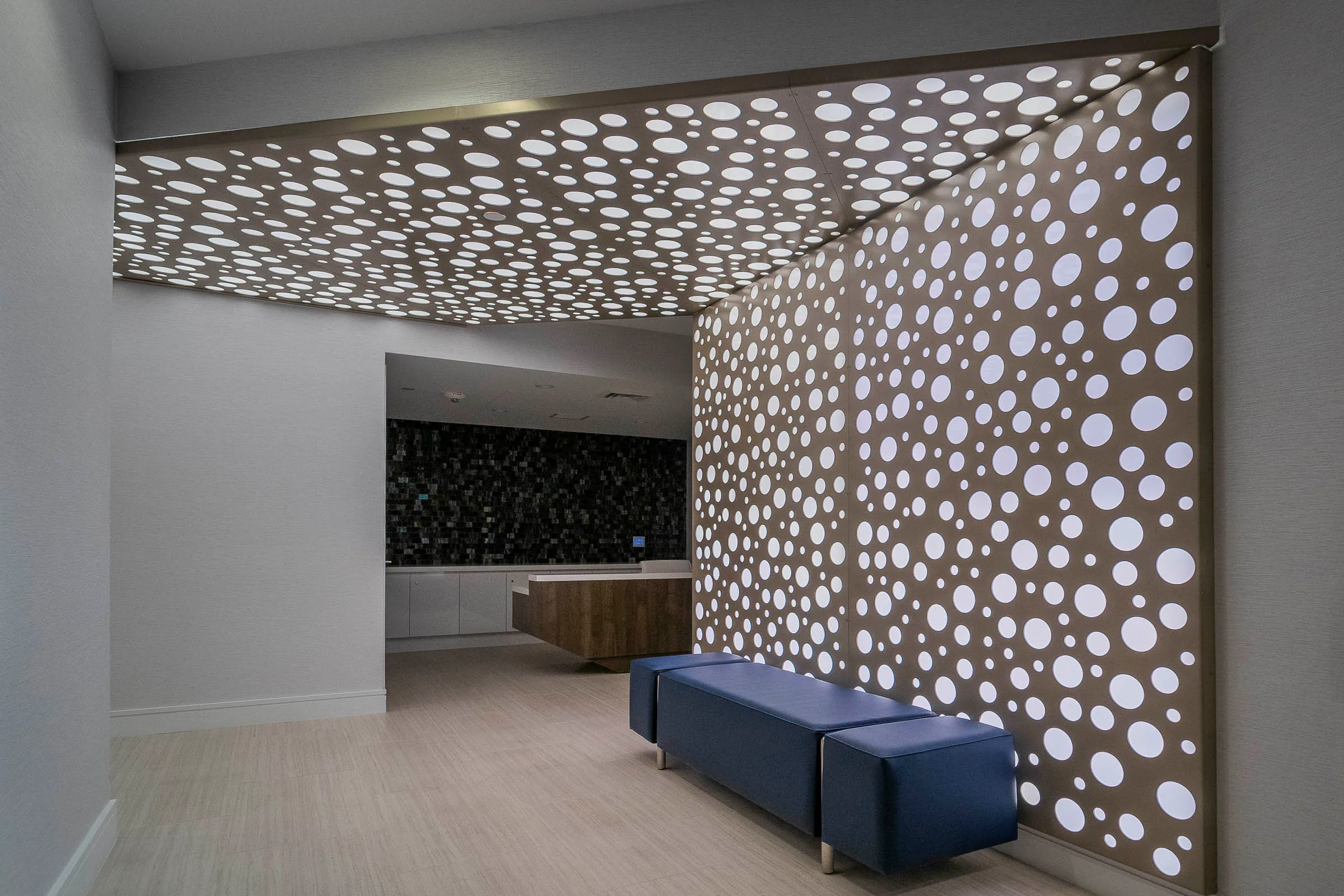 A lobby wall and ceiling of backlit perforated metal