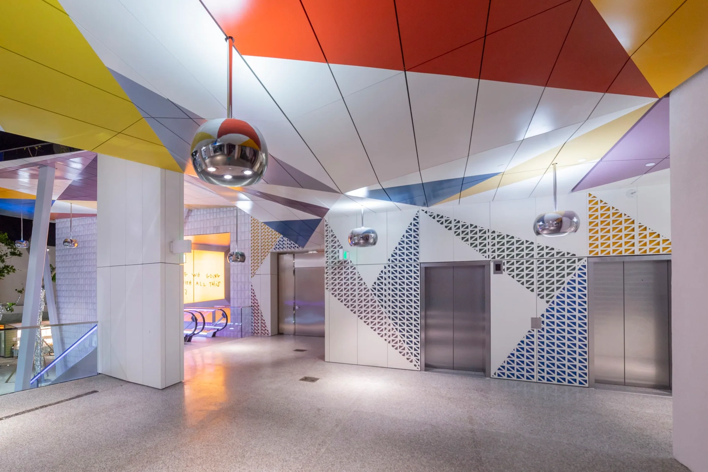 A ceiling of colored triangles over an elevator lobby
