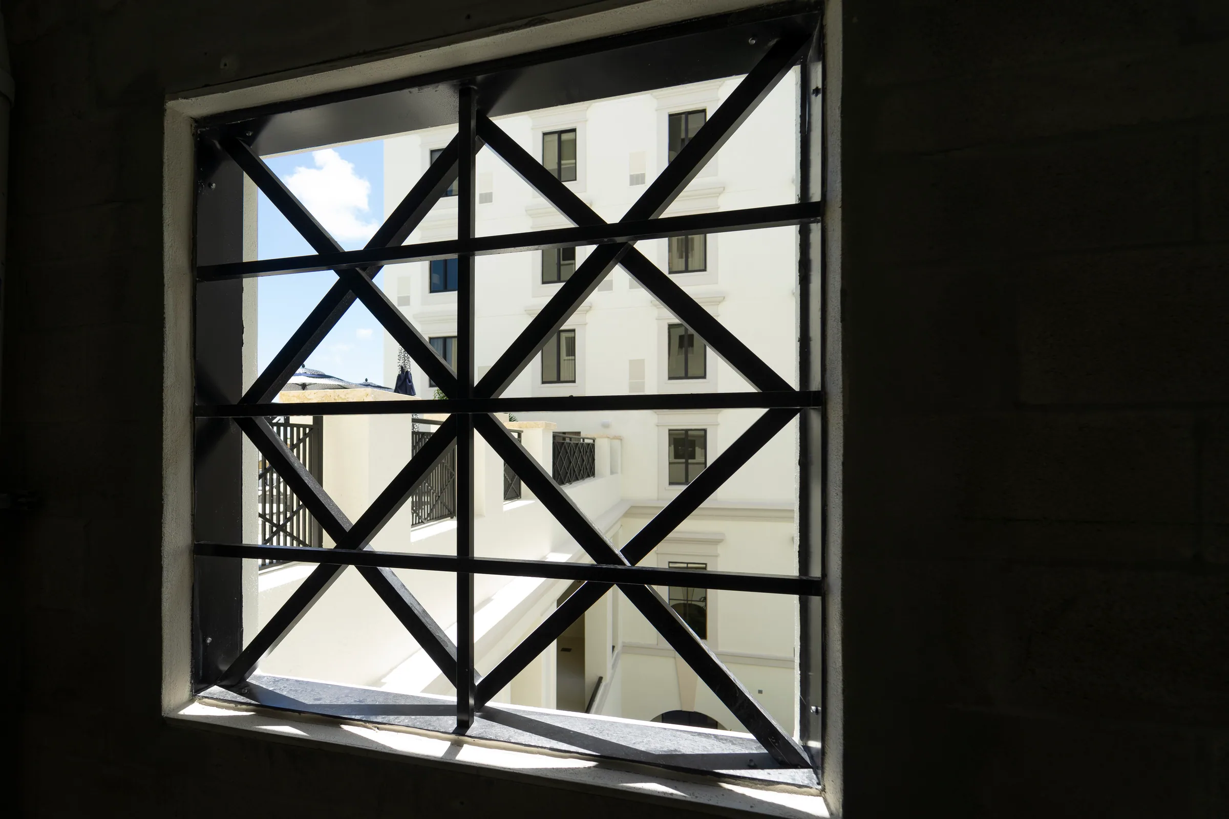 A black steel grille in a diamond pattern framing a window