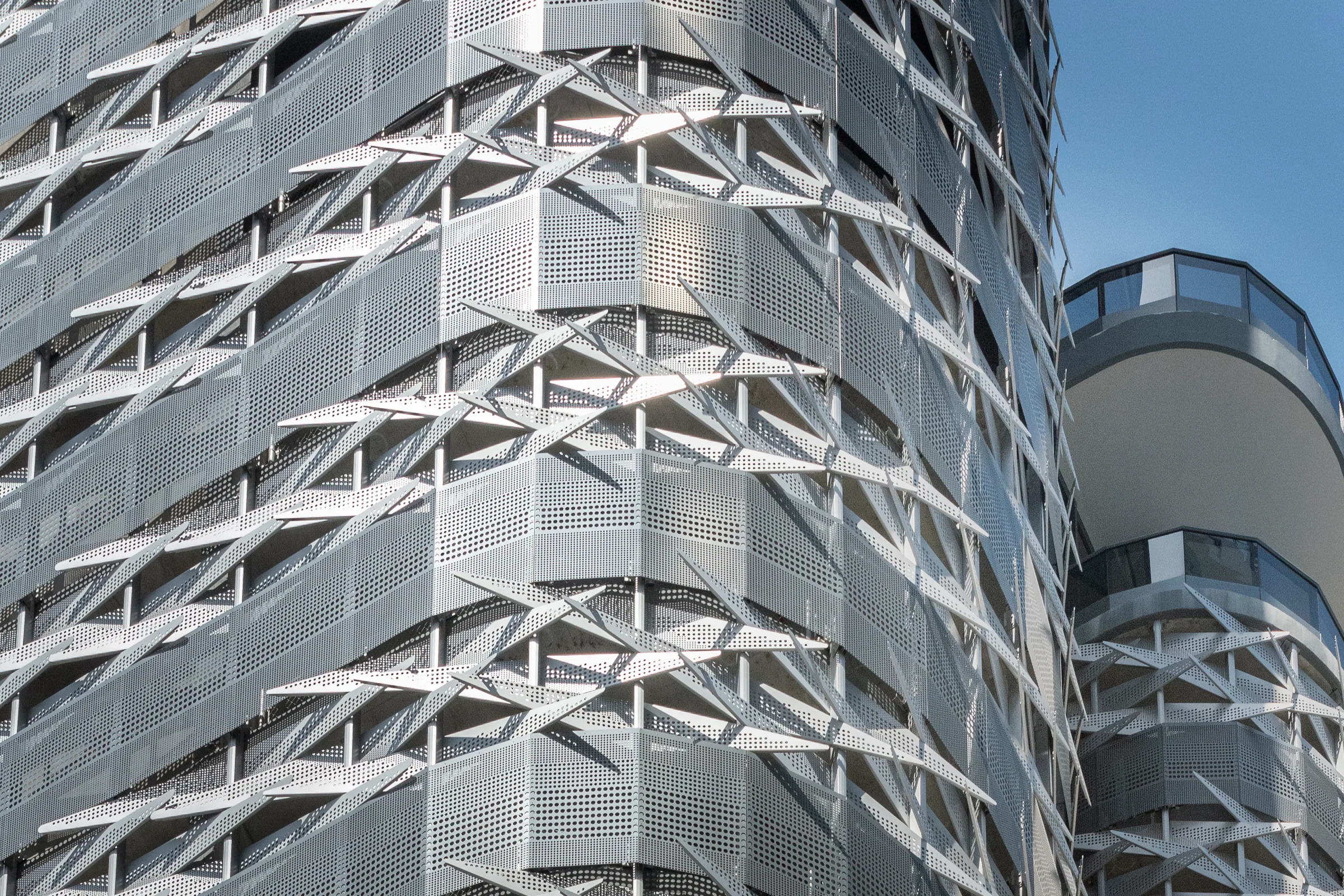 Folded perforated panels wrapping the garage’s rounded corner