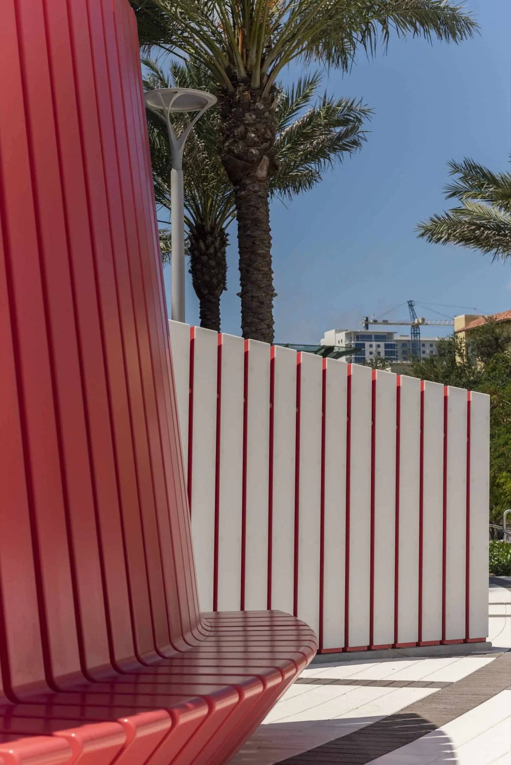 The red bench rising toward the sky beside a ribbed white wall
