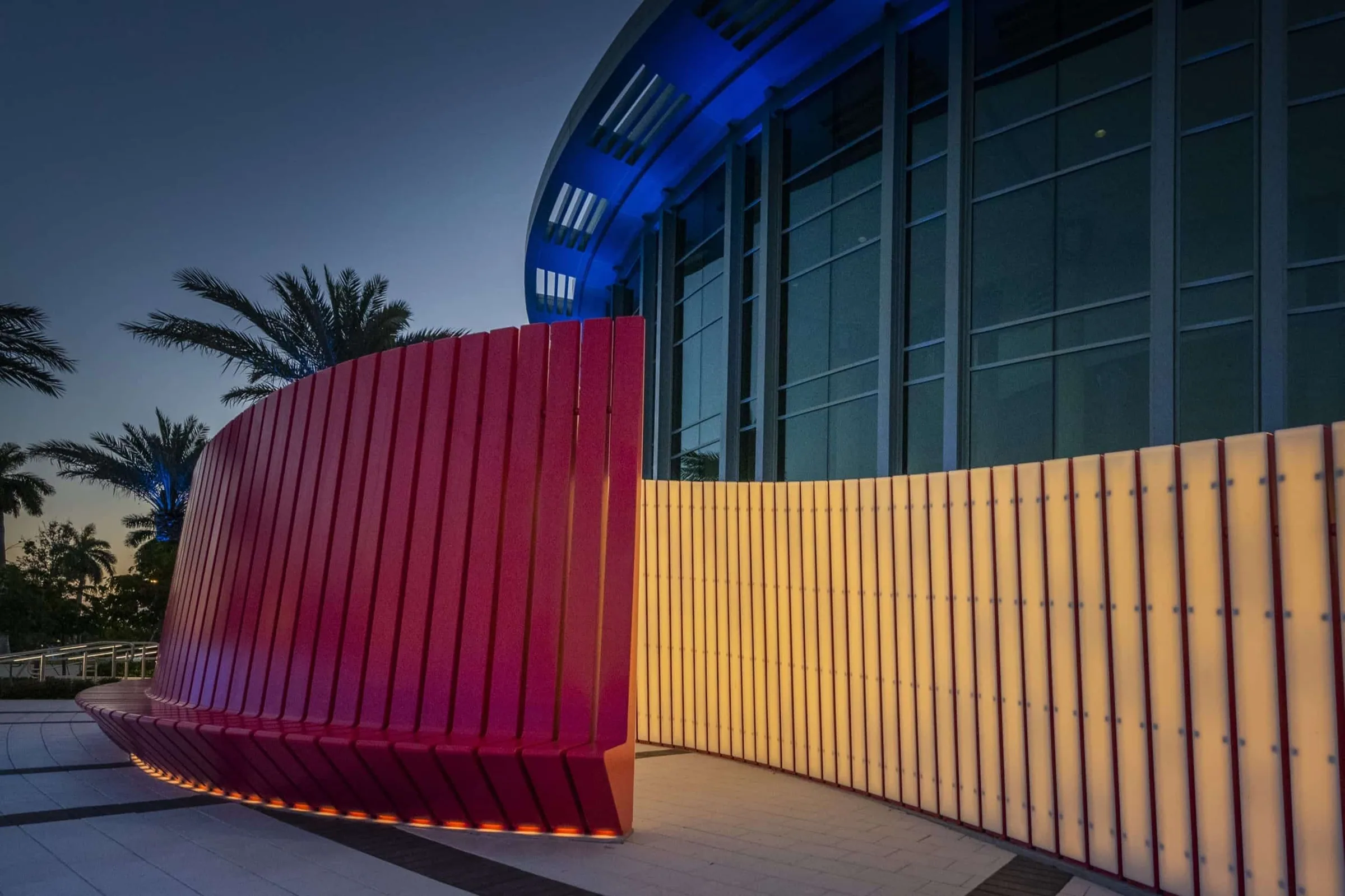 The red bench and its glowing back wall at dusk outside the Kravis Center