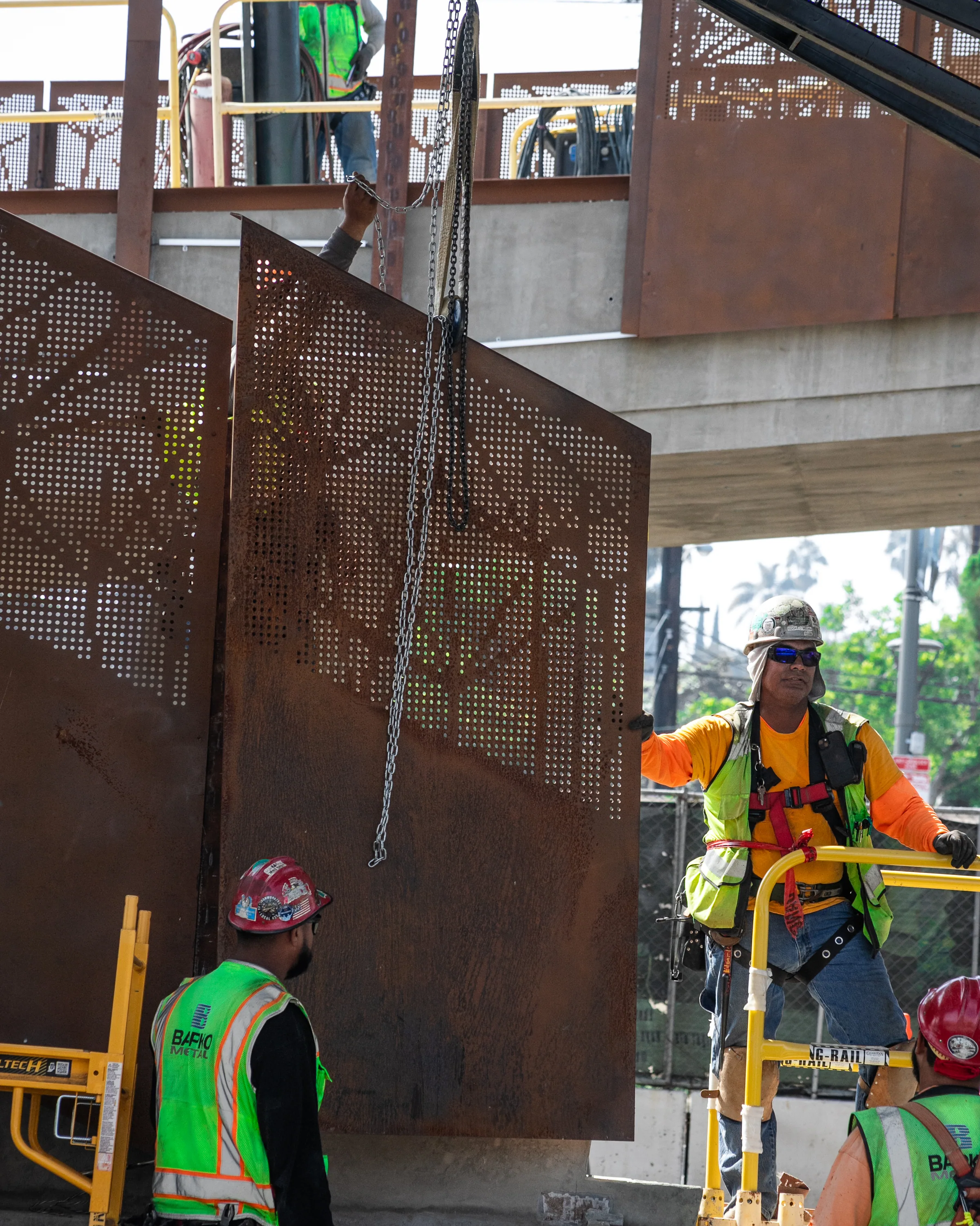 Ironworkers guiding a perforated steel panel into place