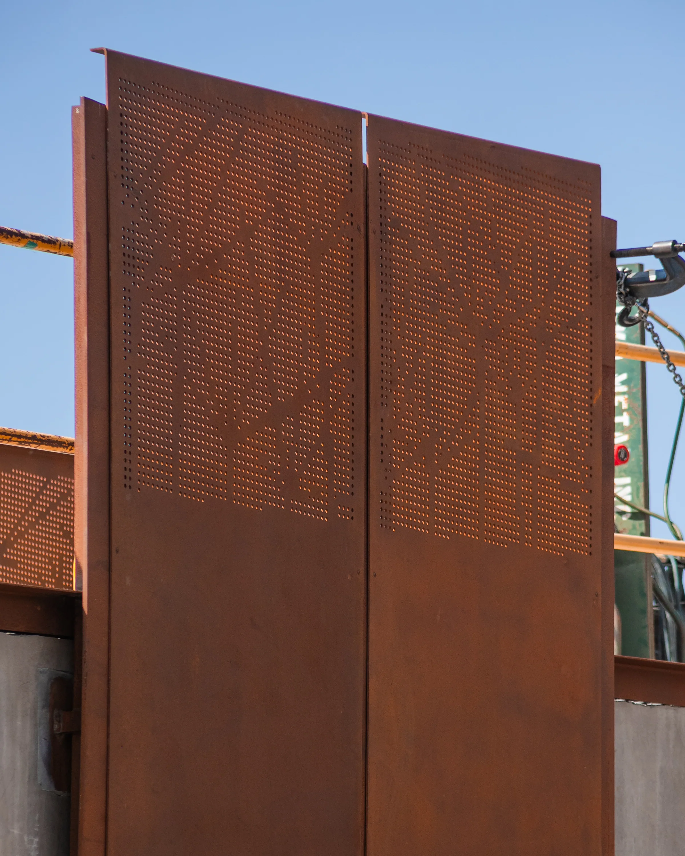 Two tall perforated panels standing against the sky