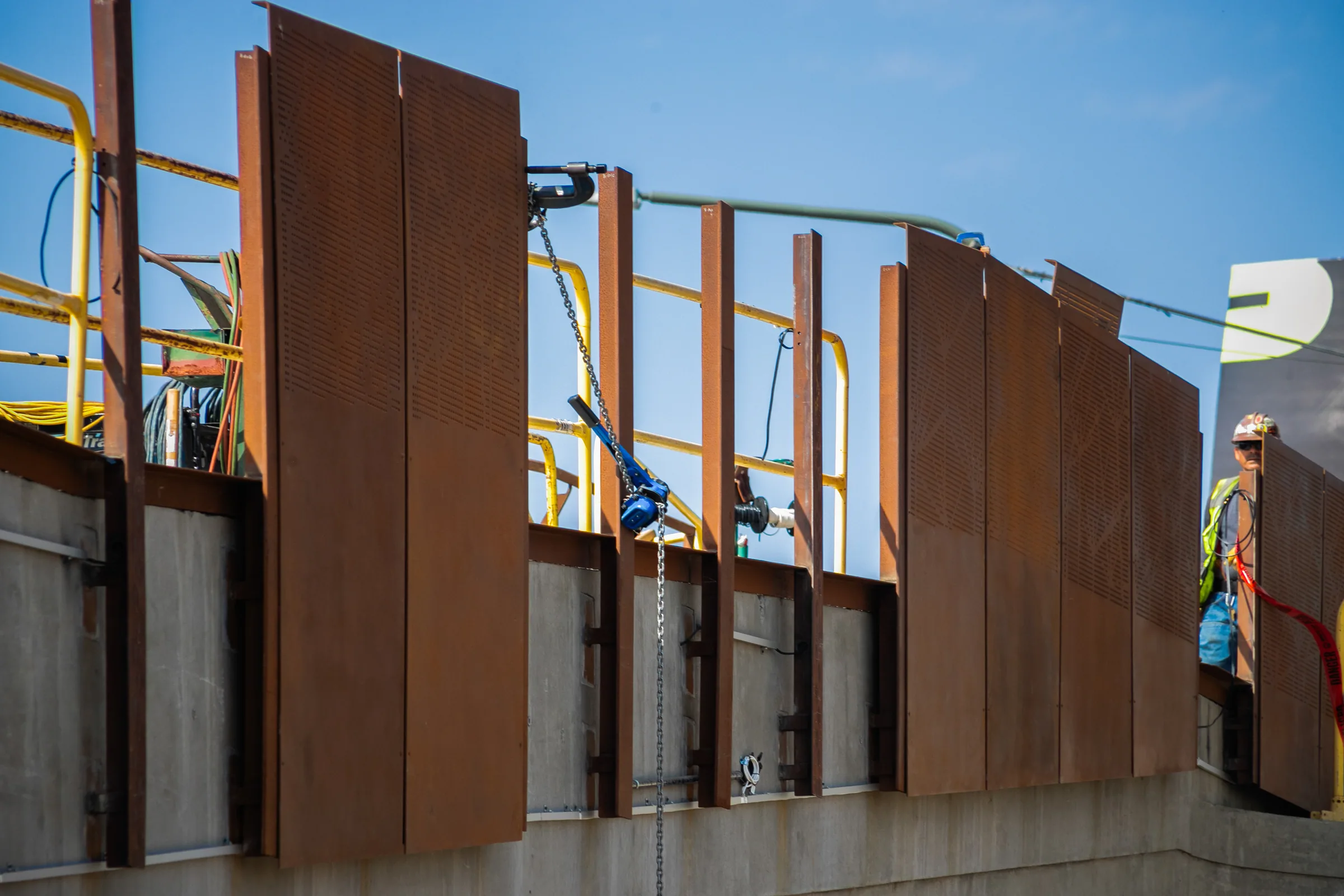 Weathering steel panels being set along a concrete wall