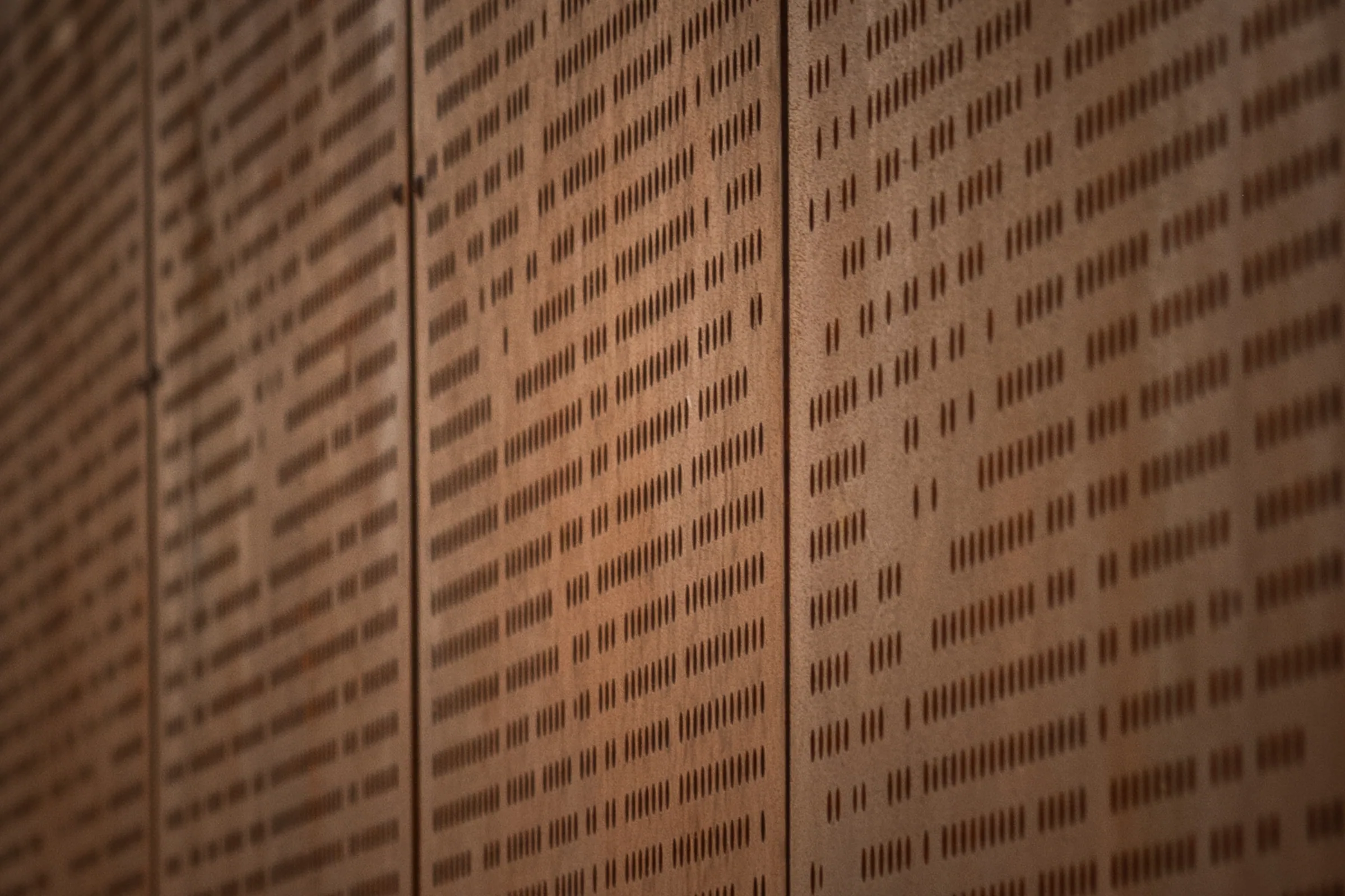 Close on rows of slotted perforations in rusted steel
