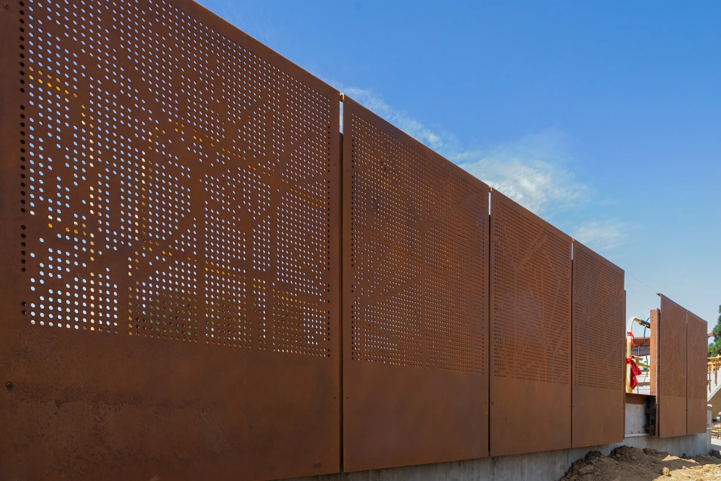 A wall of perforated weathering steel panels running into the distance