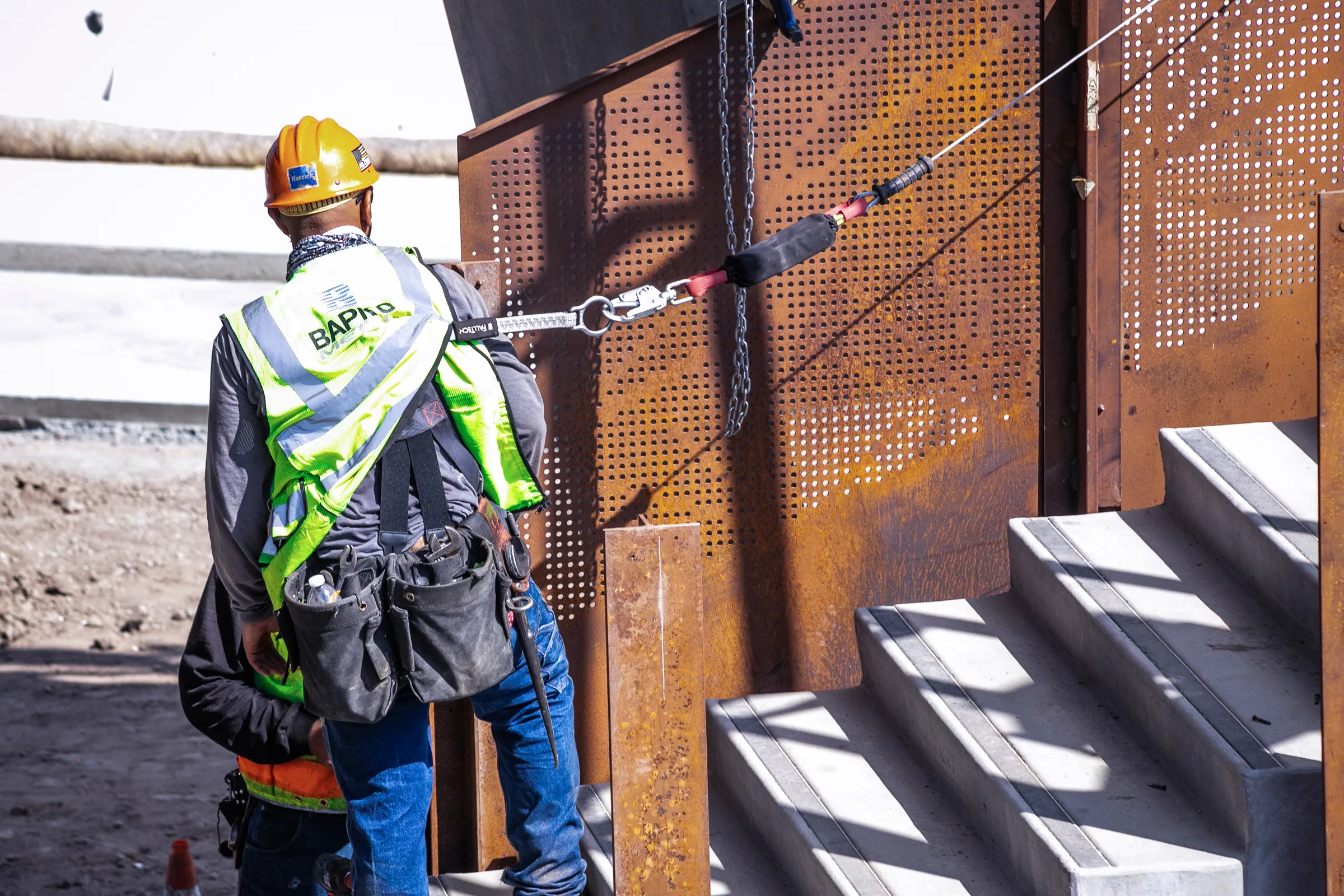 An ironworker fastening a perforated panel beside new steps