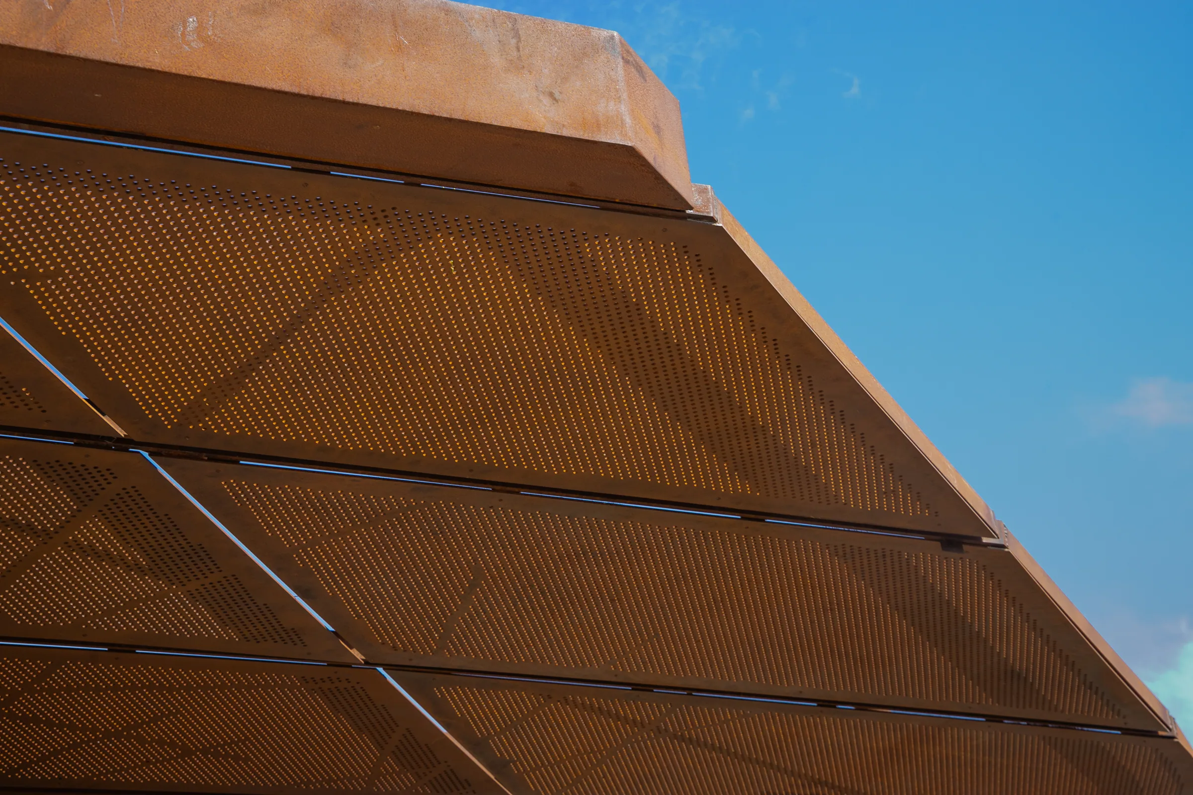 The underside of the canopy, perforated weathering steel against the sky