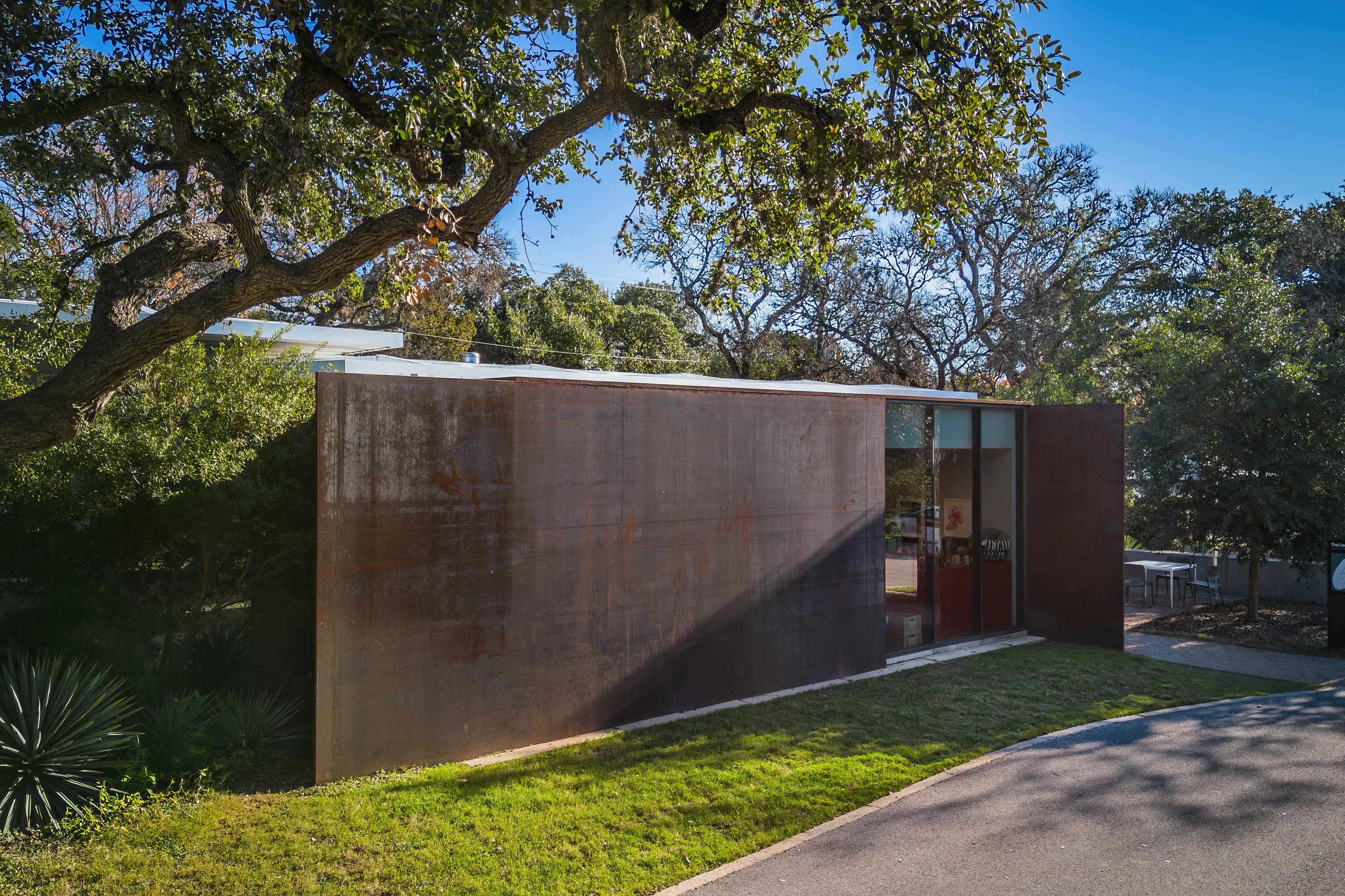 A weathering steel wall under the branches of a live oak