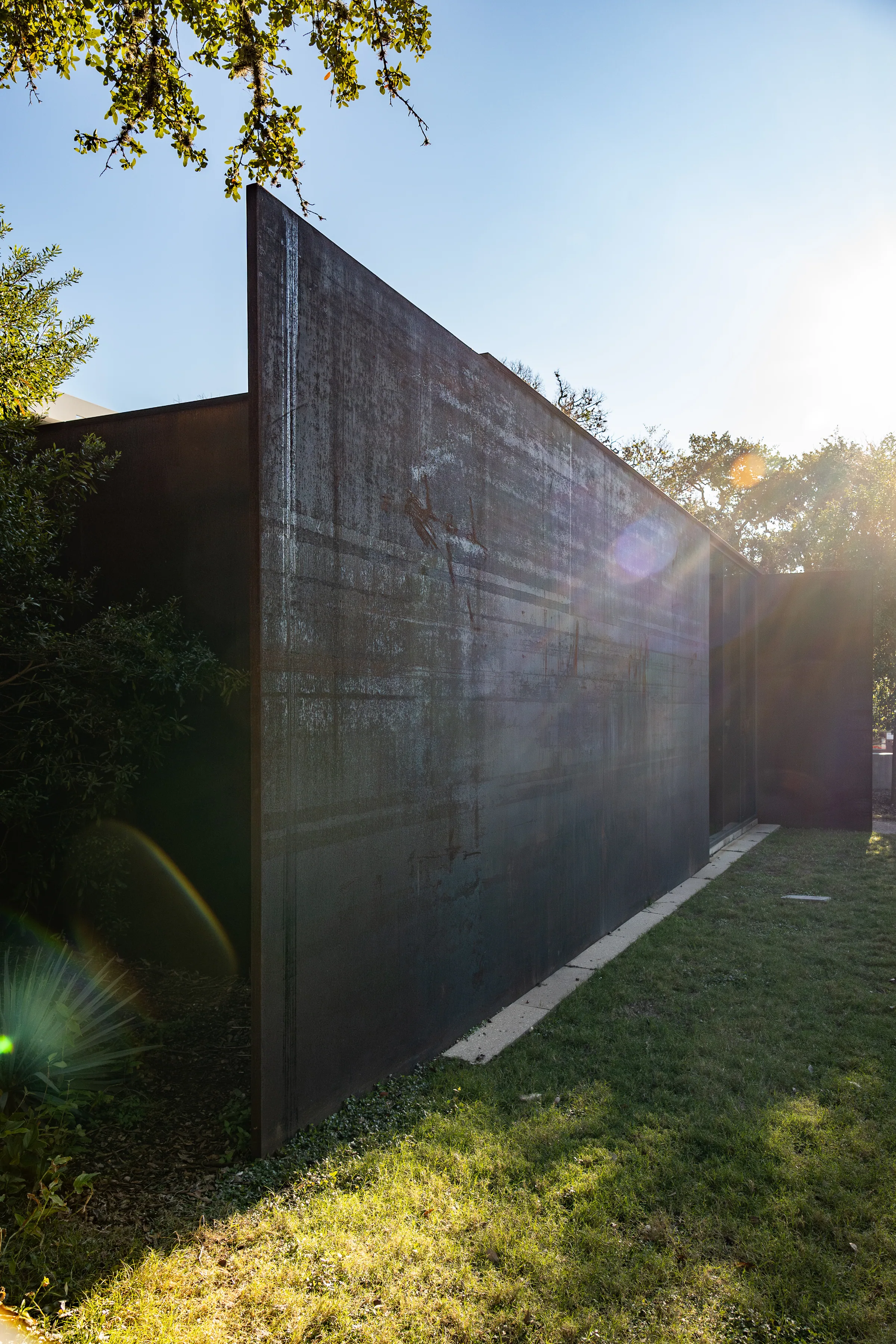 Sun breaking past a tall steel wall