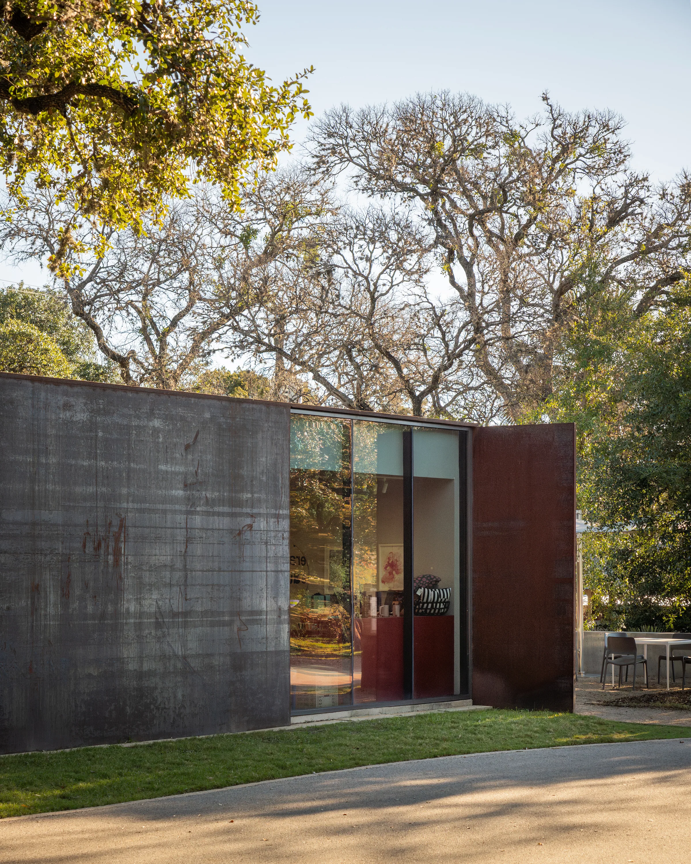 A small steel and glass pavilion under the trees