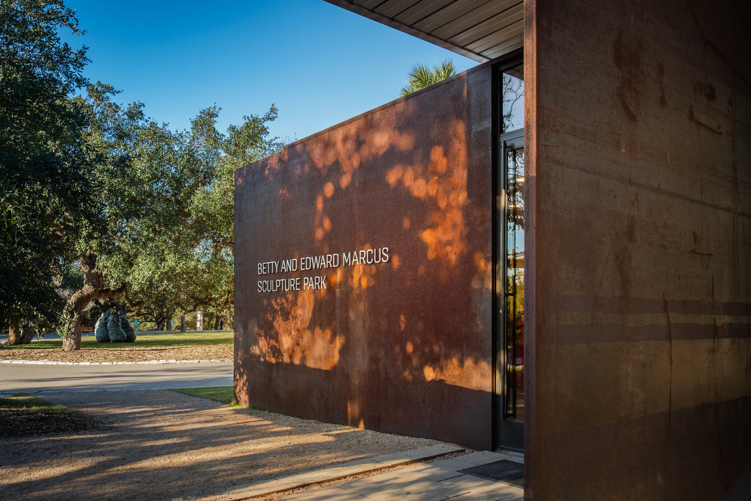 The lettered steel wall under the trees