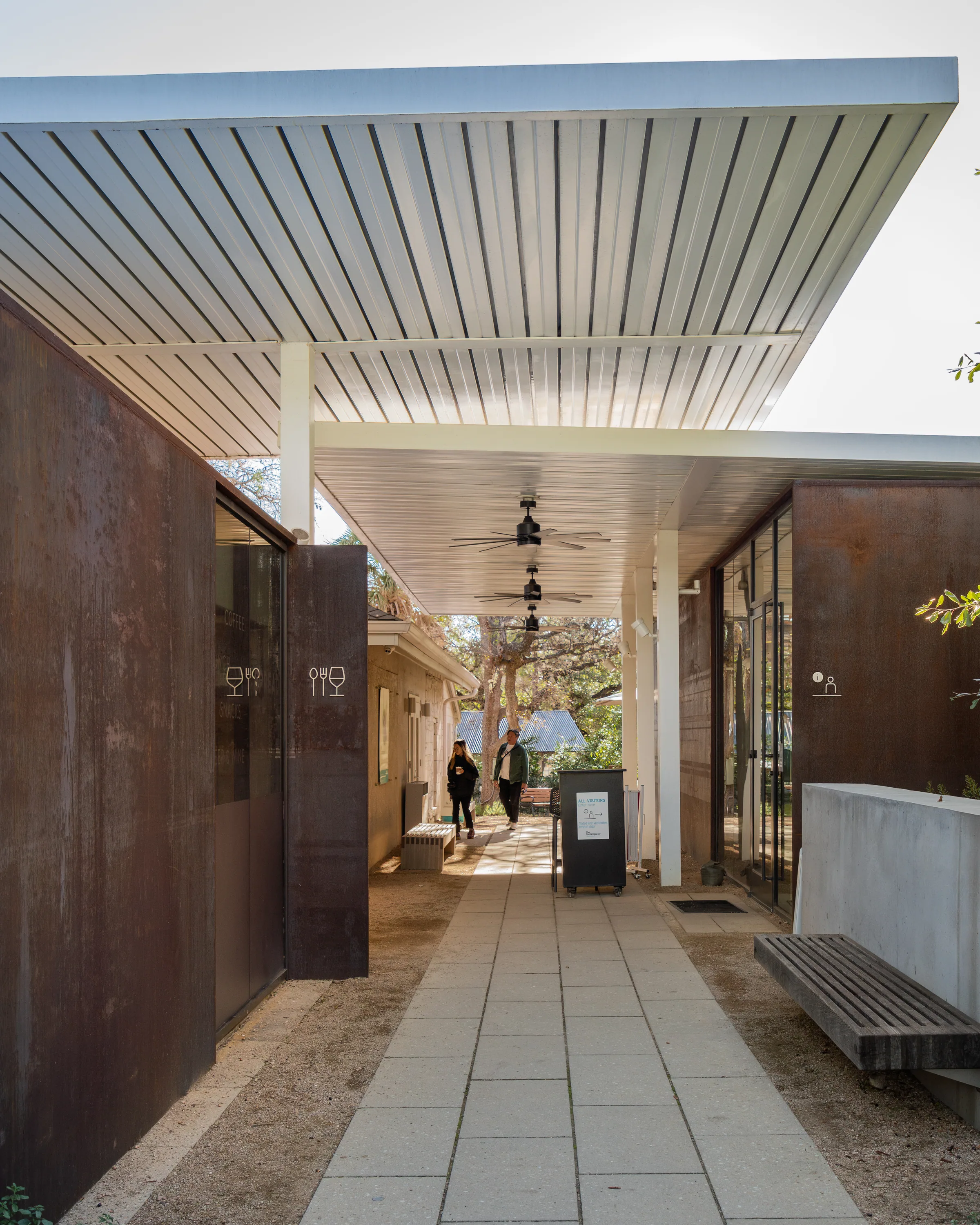 A covered walkway between steel walls and glass