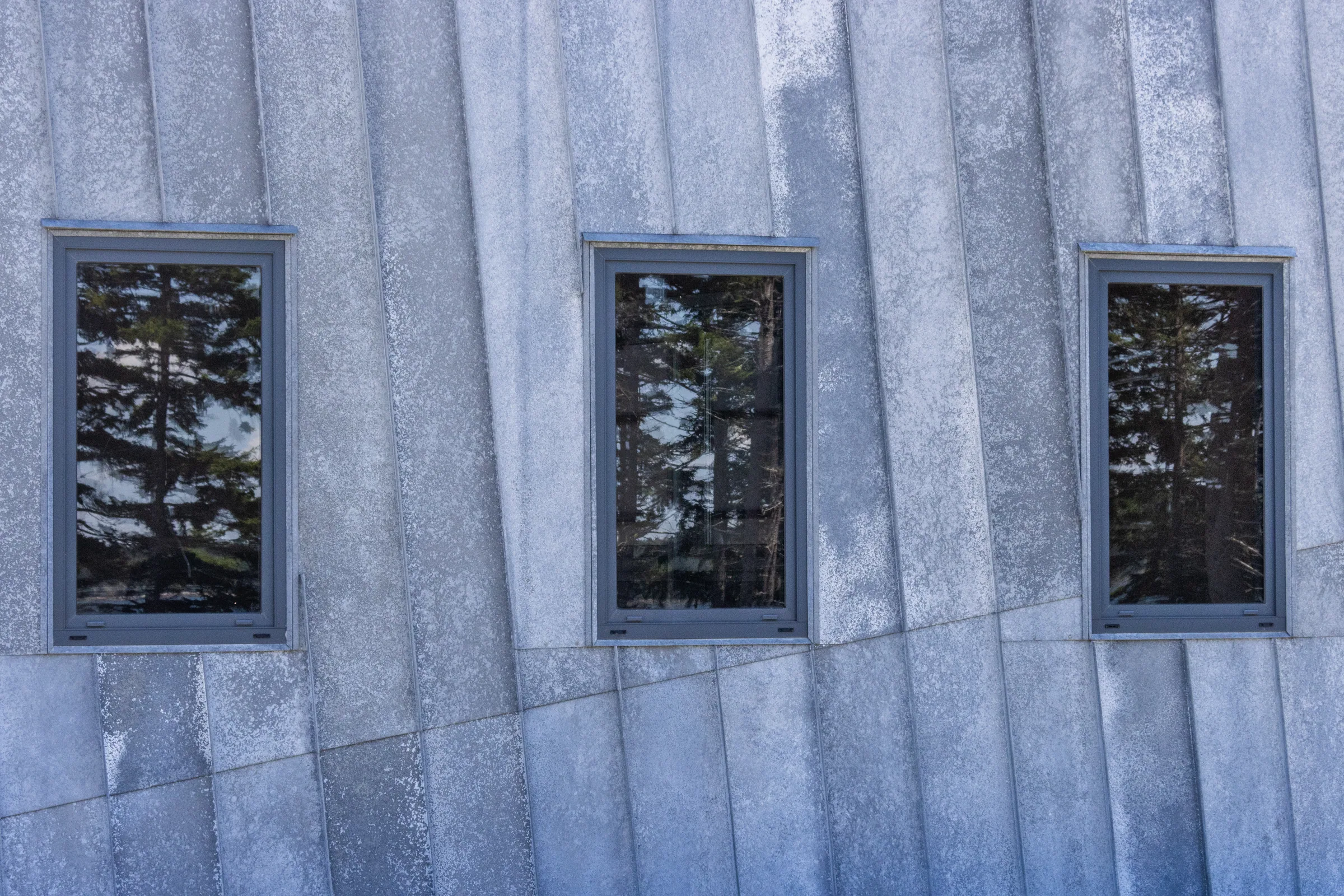 Three windows in a weathered zinc wall