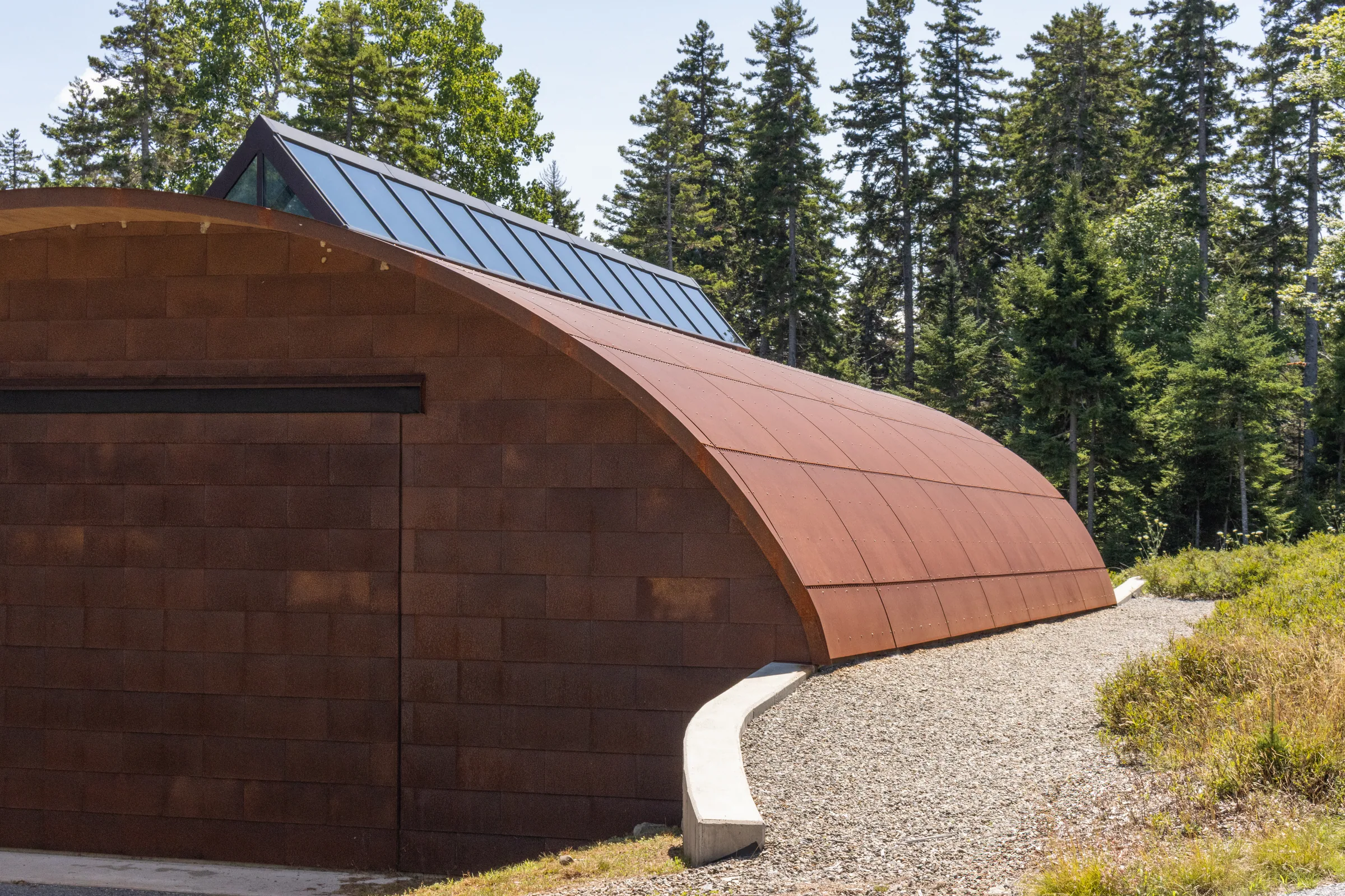 A weathering steel barrel vault curving along a gravel path