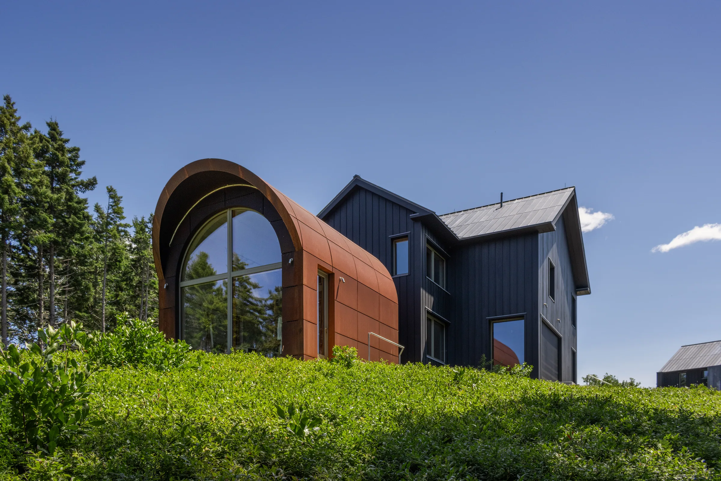 The steel-clad arch beside the dark house on a green slope
