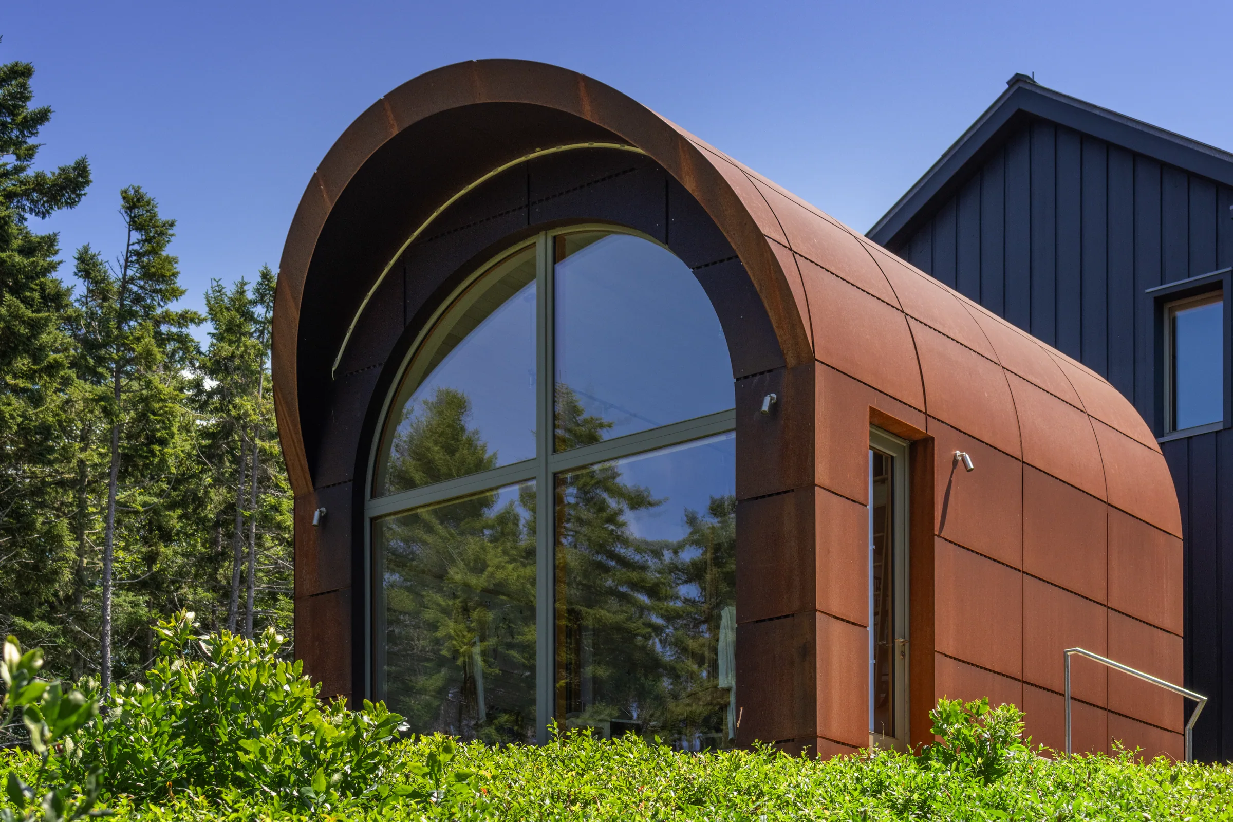 A tall arched window set in the weathering steel shell