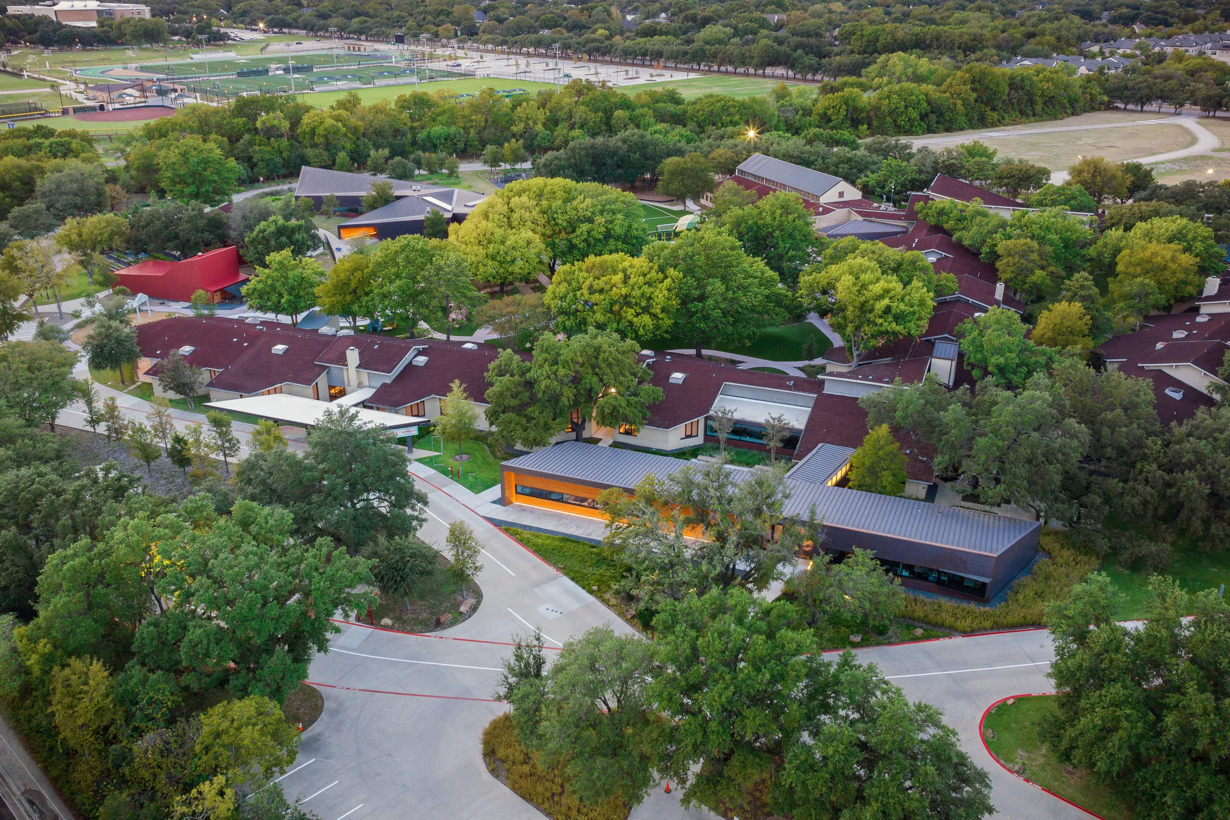 An aerial of the wooded campus with the copper buildings among the trees