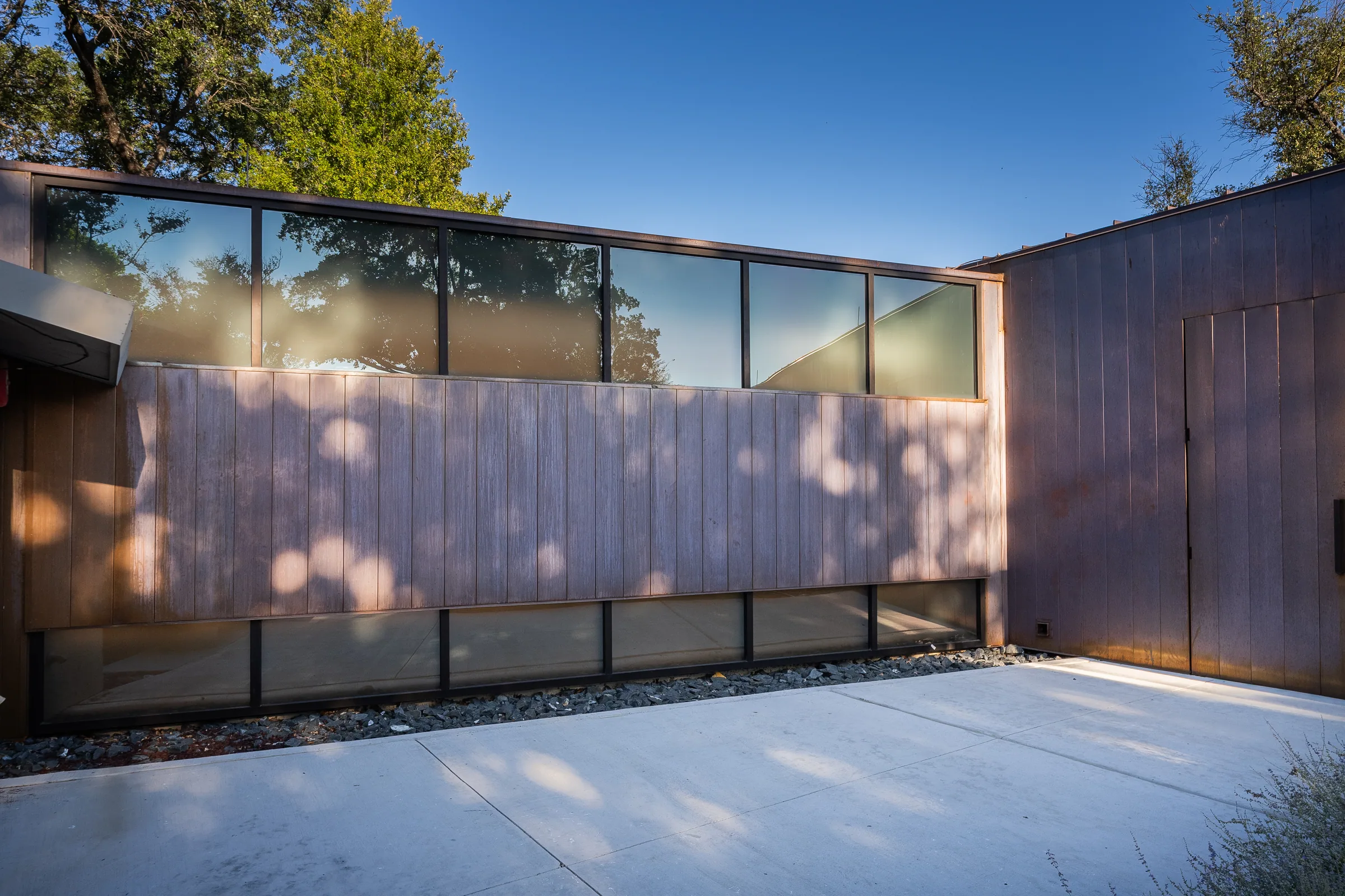 Dappled shade on copper panels above a row of windows