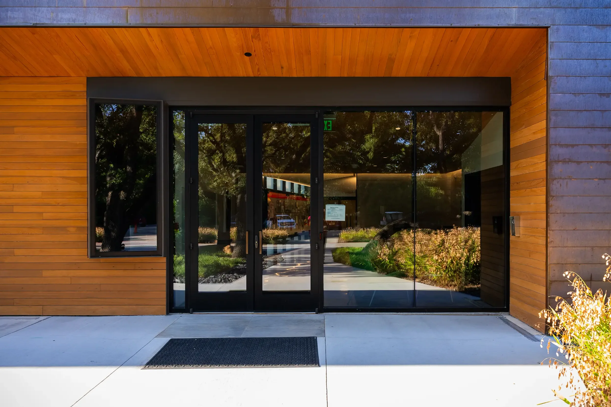 A glass entry framed in wood under a copper edge