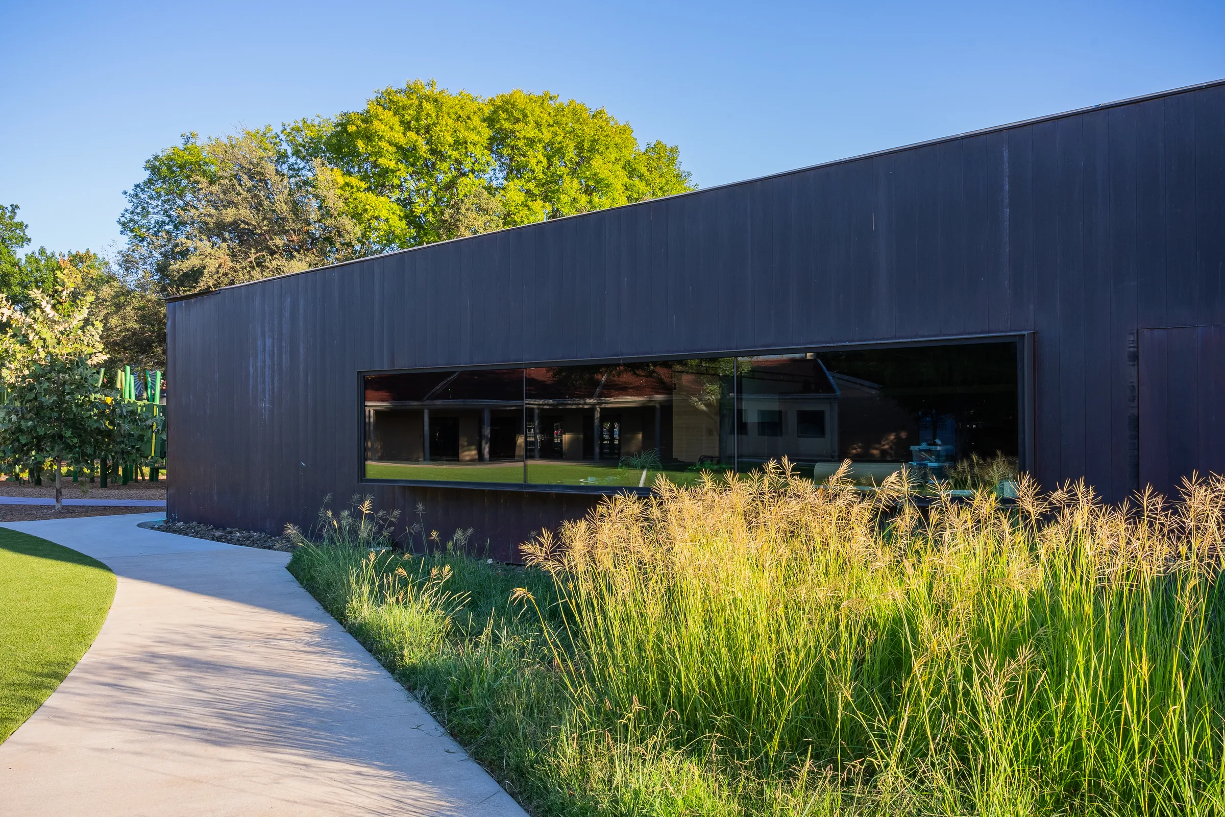 A dark copper building above tall grasses