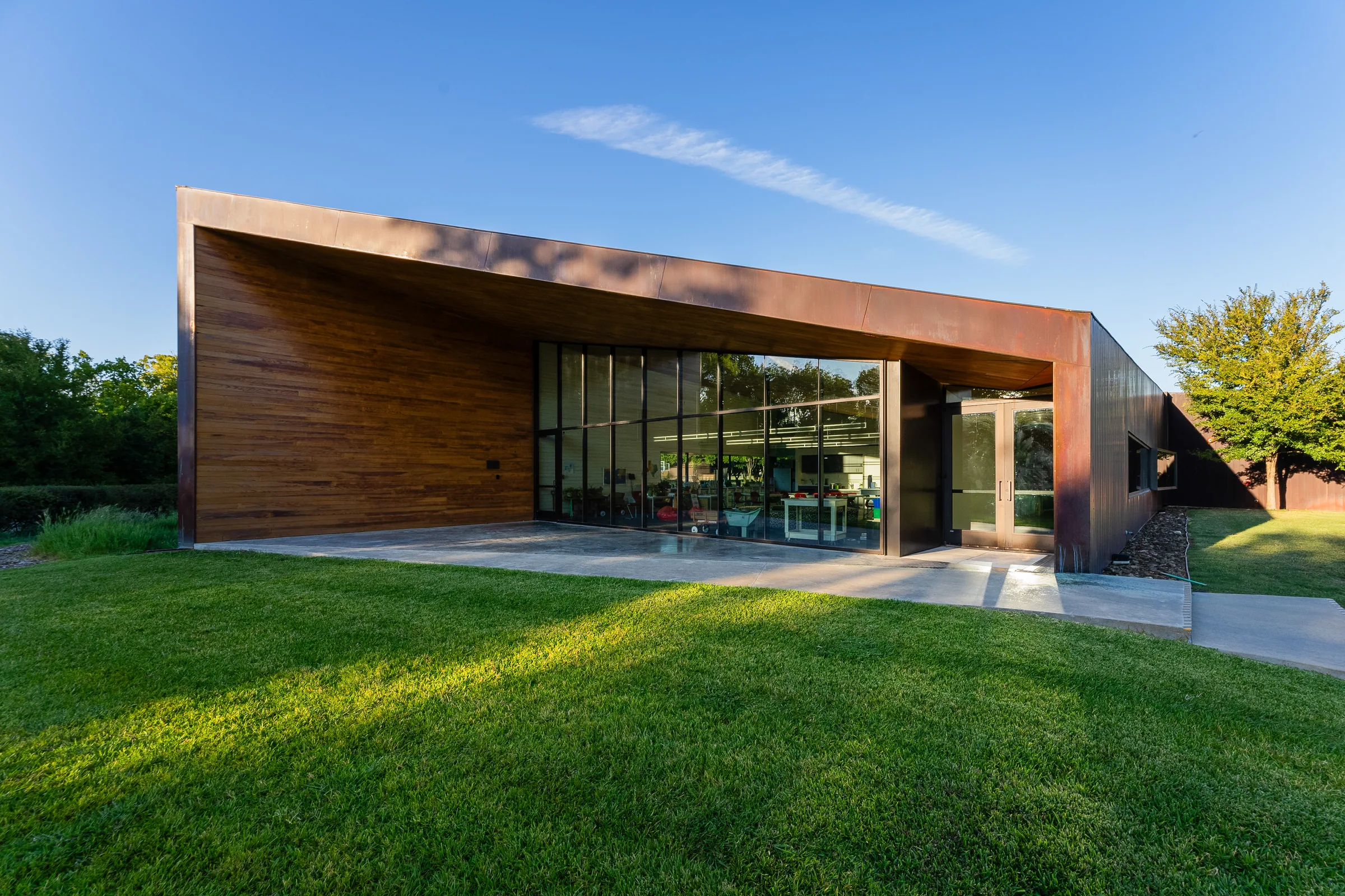 A copper and wood building opening onto a lawn