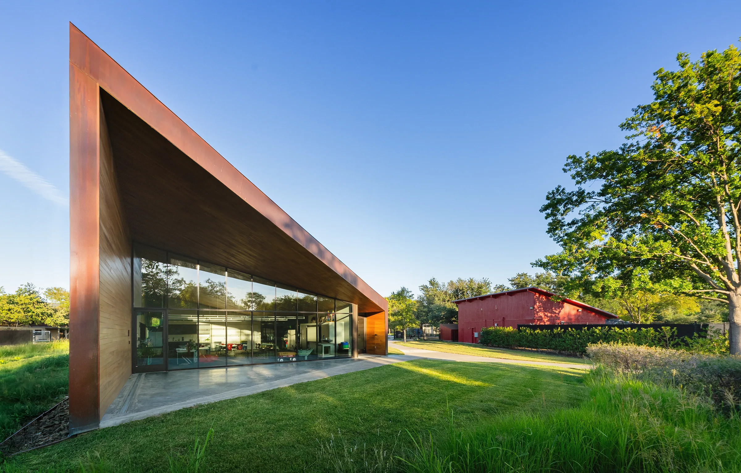 The sharp copper roof edge over a glass wall, a red barn beyond