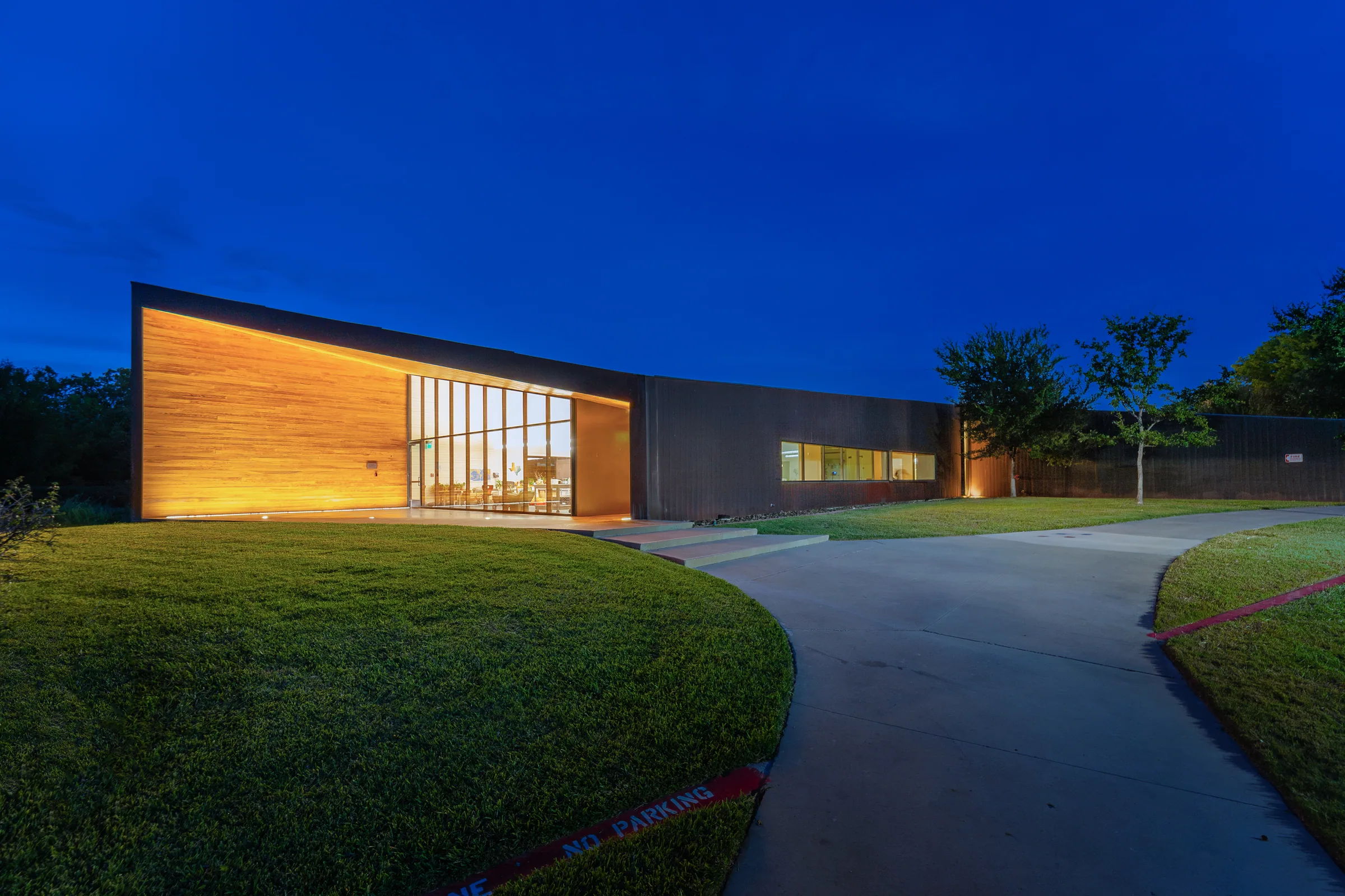A copper building at blue hour, its wood-clad end lit up
