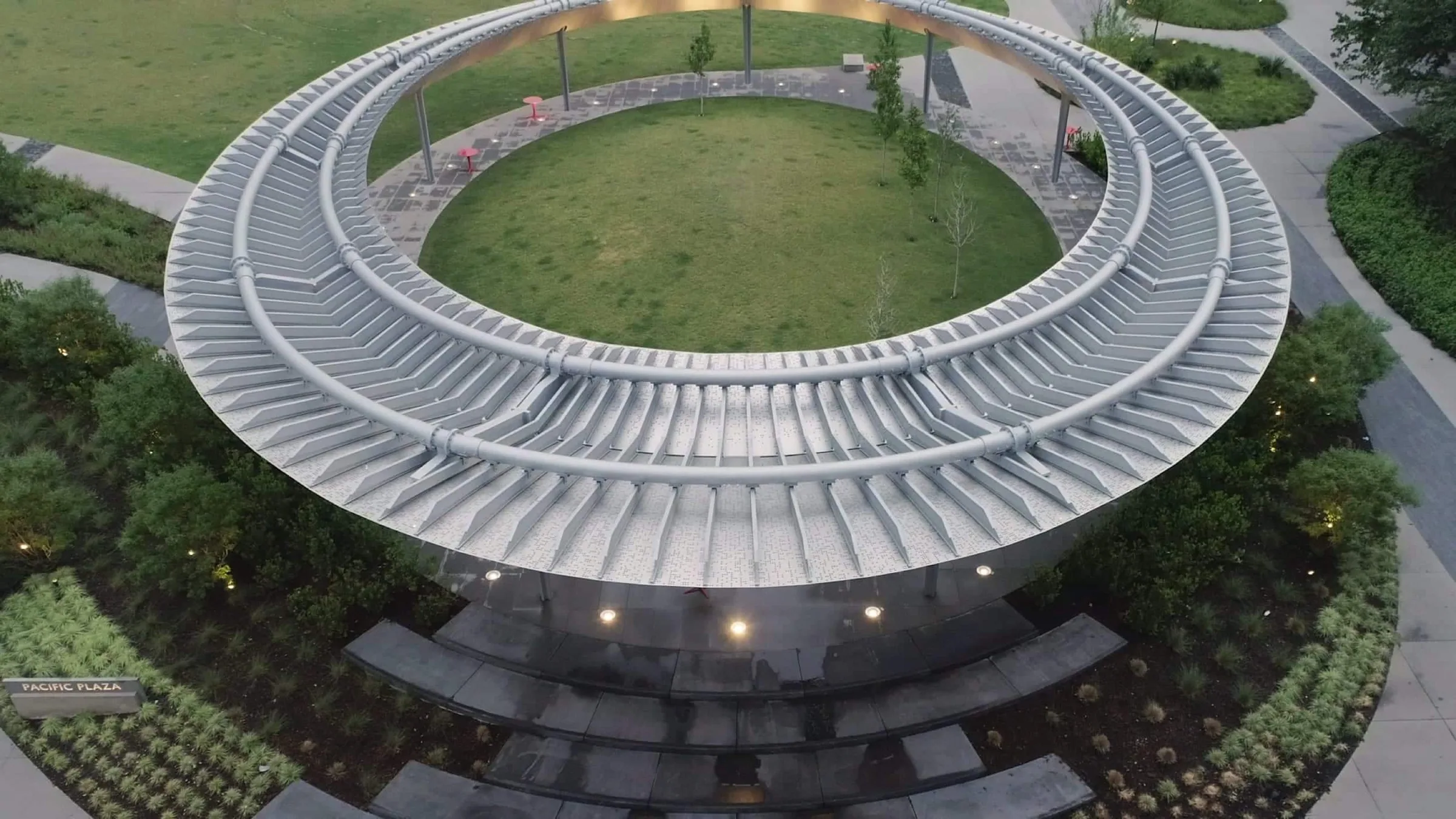 The ring-shaped stainless pavilion from above at dusk