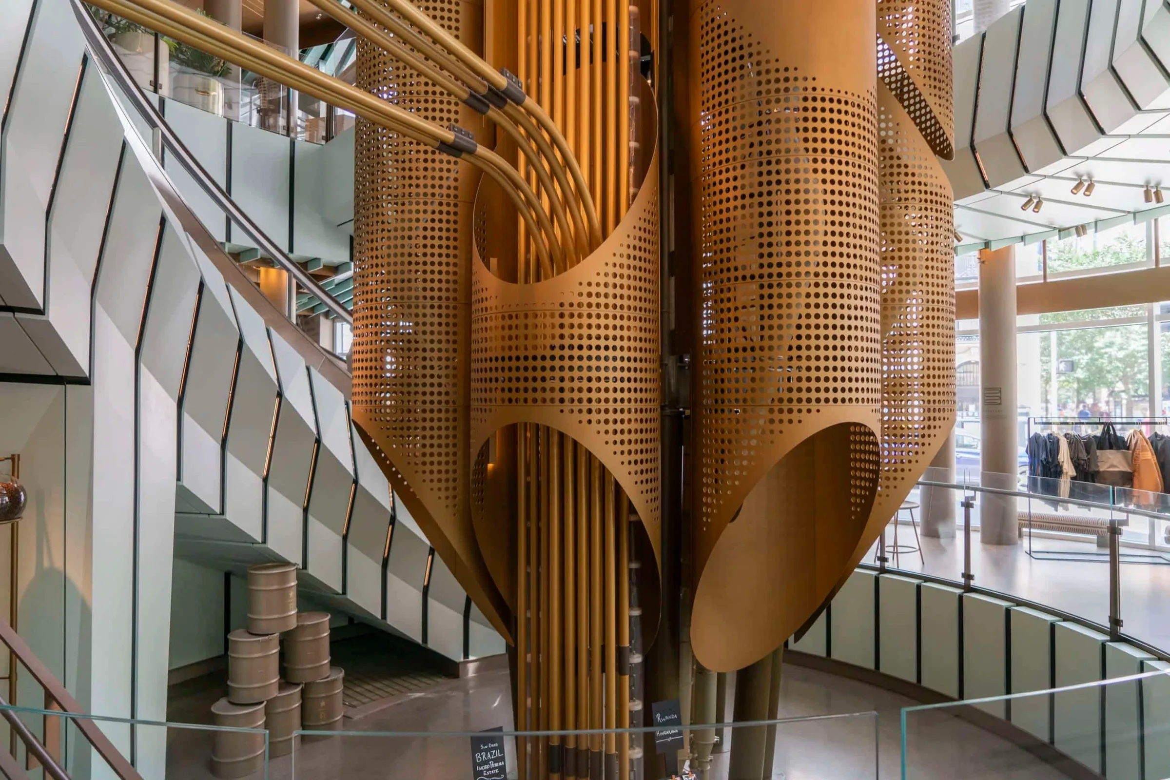 The perforated copper-colored cask rising through the Roastery’s spiral stair