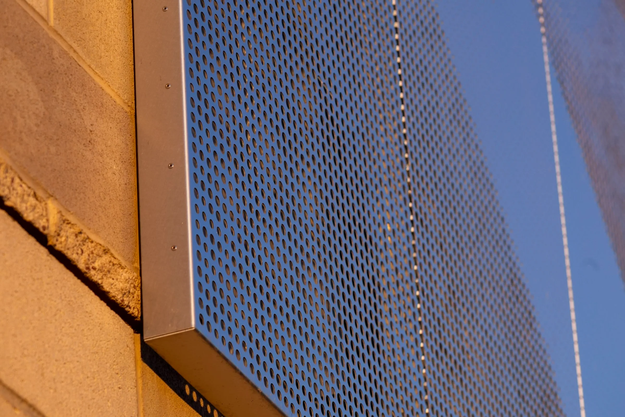 The perforated panel’s corner against a blue sky