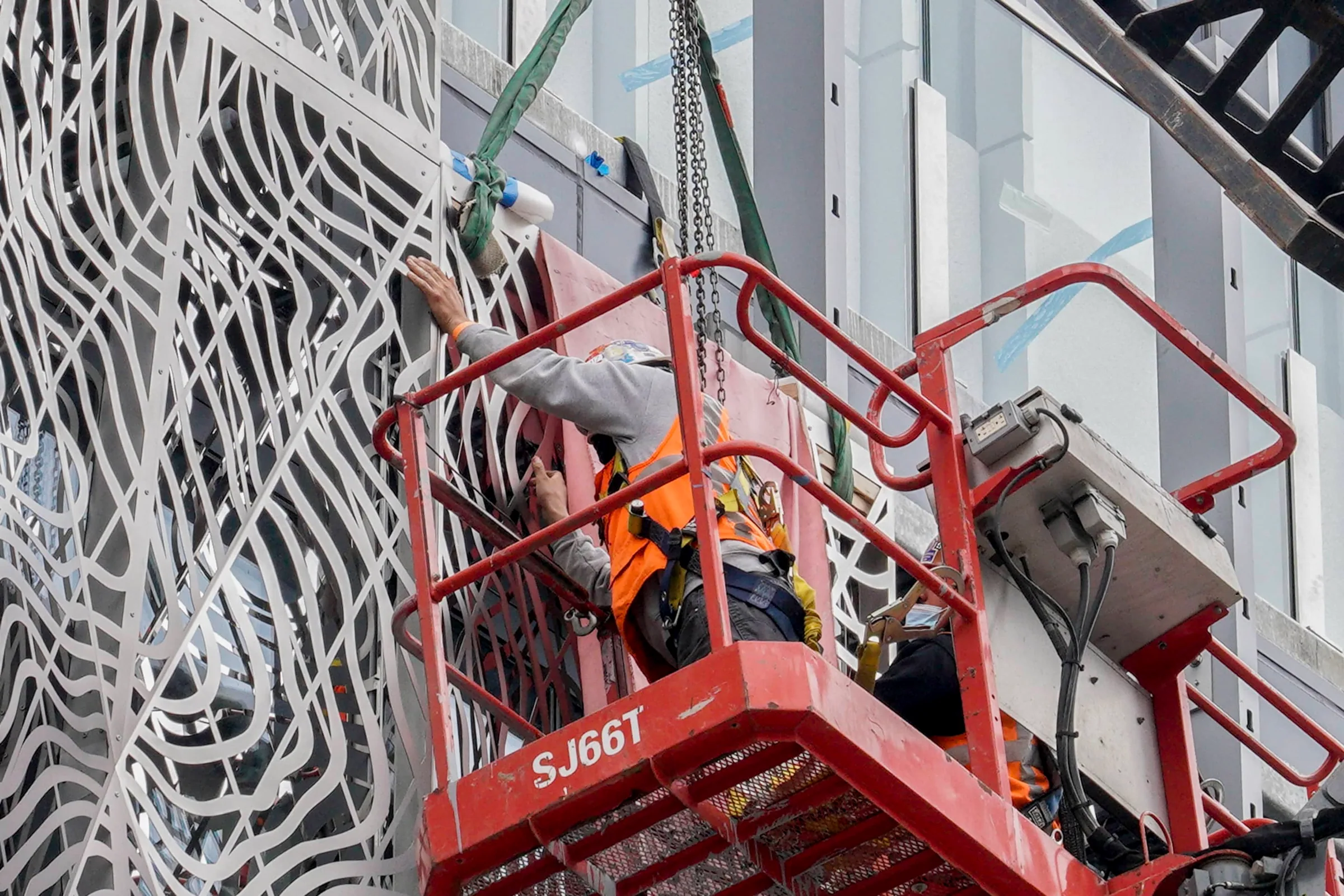 Installers in a lift fixing panels of the stainless steel screen