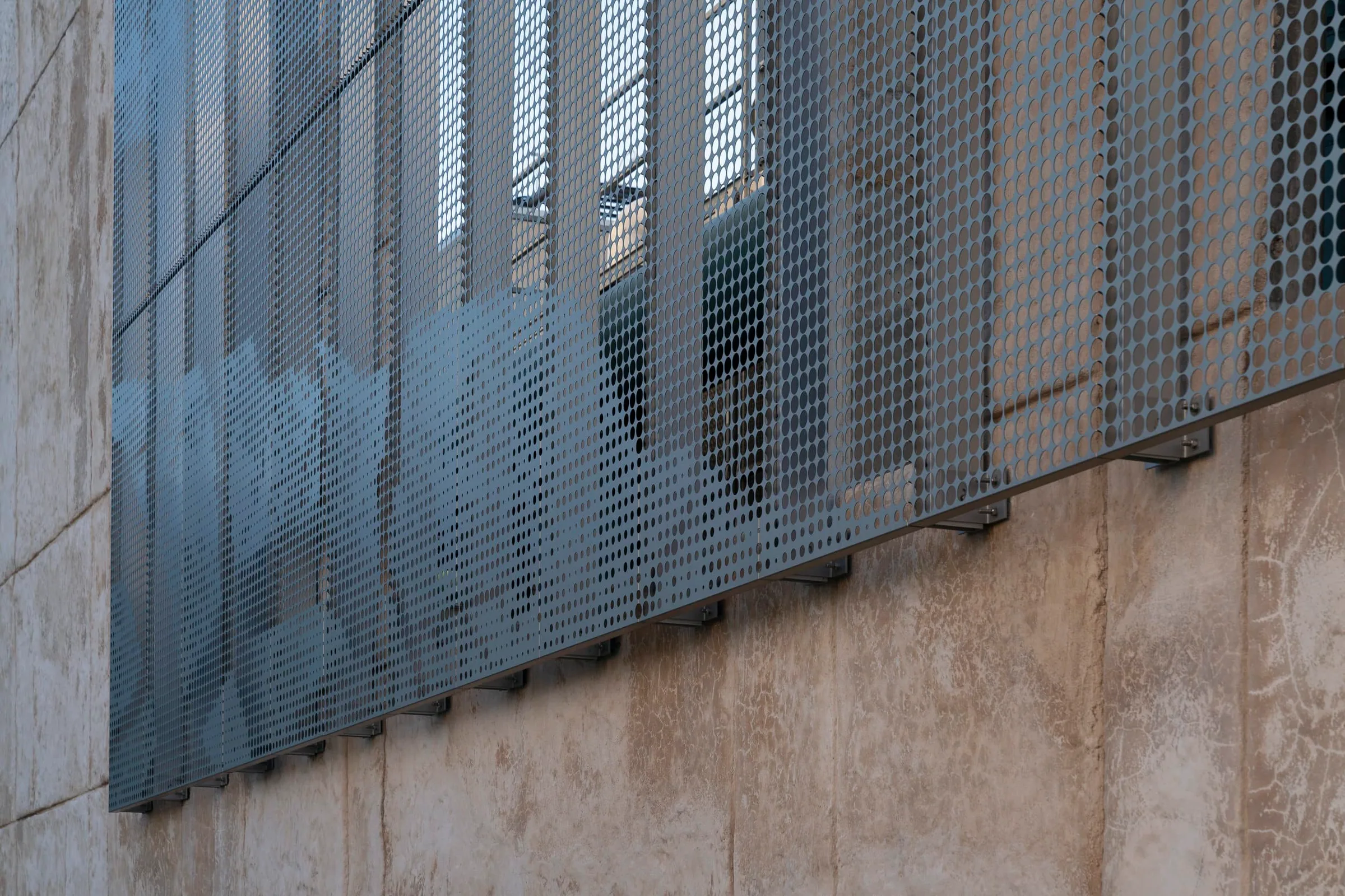 The perforated screen standing off the stone wall