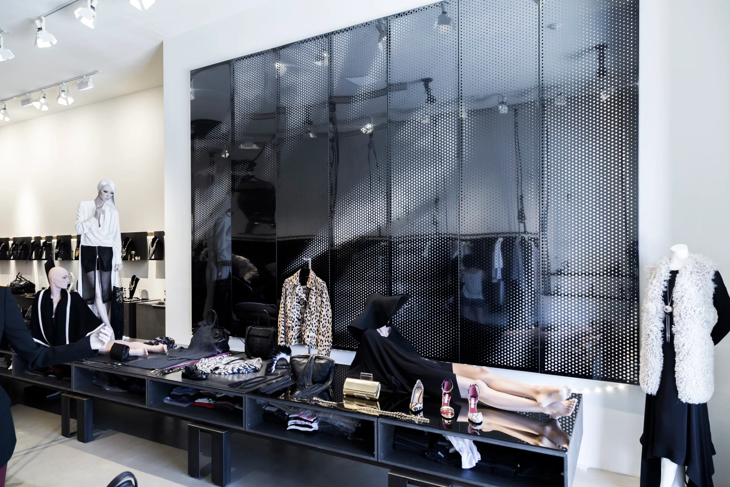 A black perforated steel wall behind racks of clothes