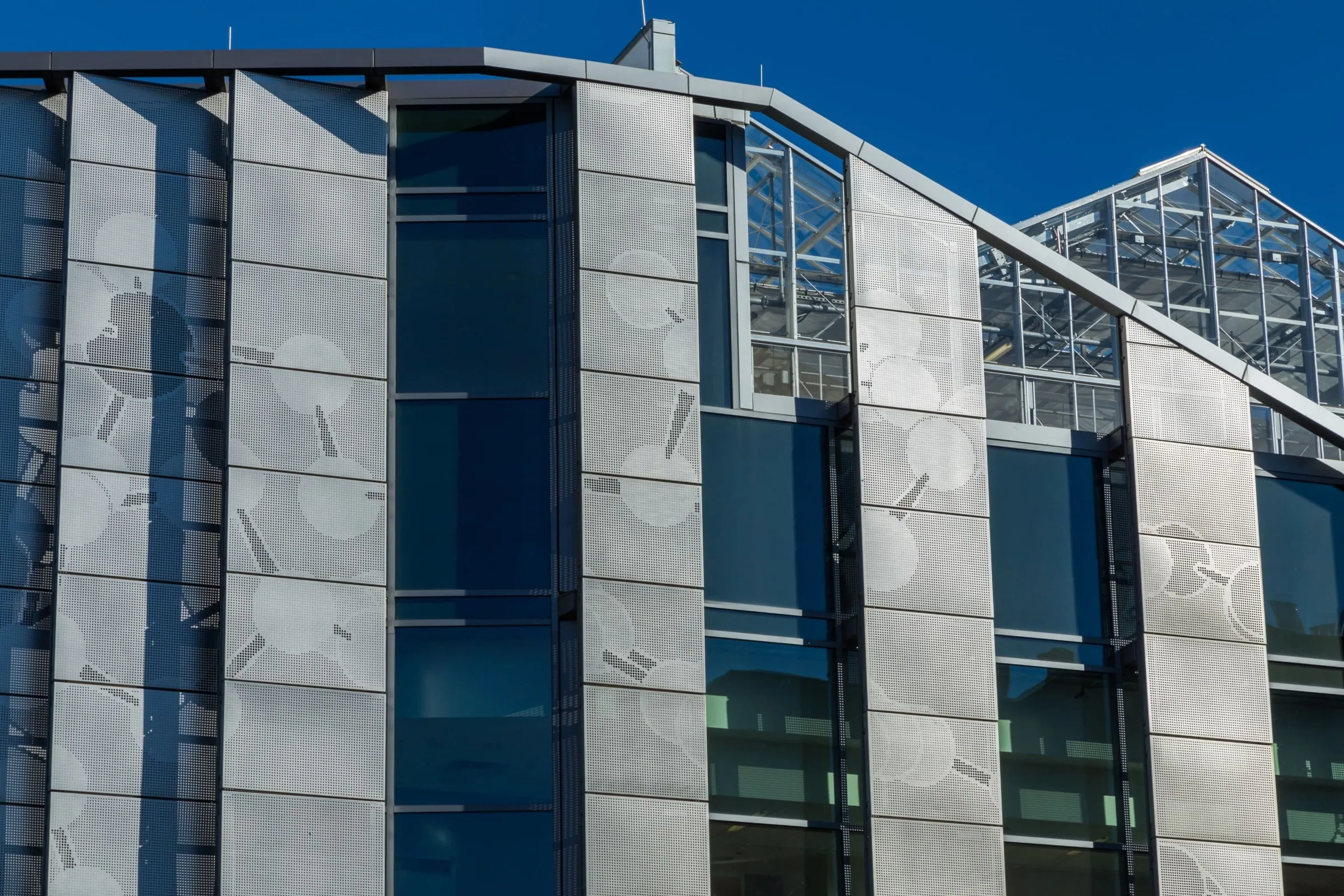 Perforated steel panels between glass bays