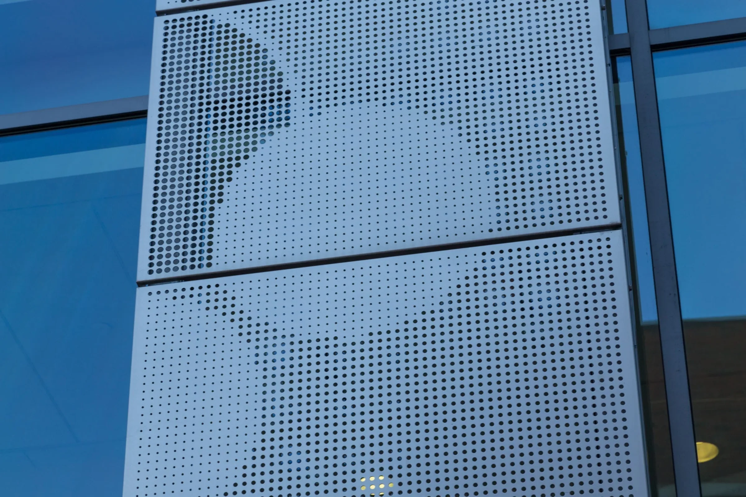 A pattern of large dots in the perforated steel, up close