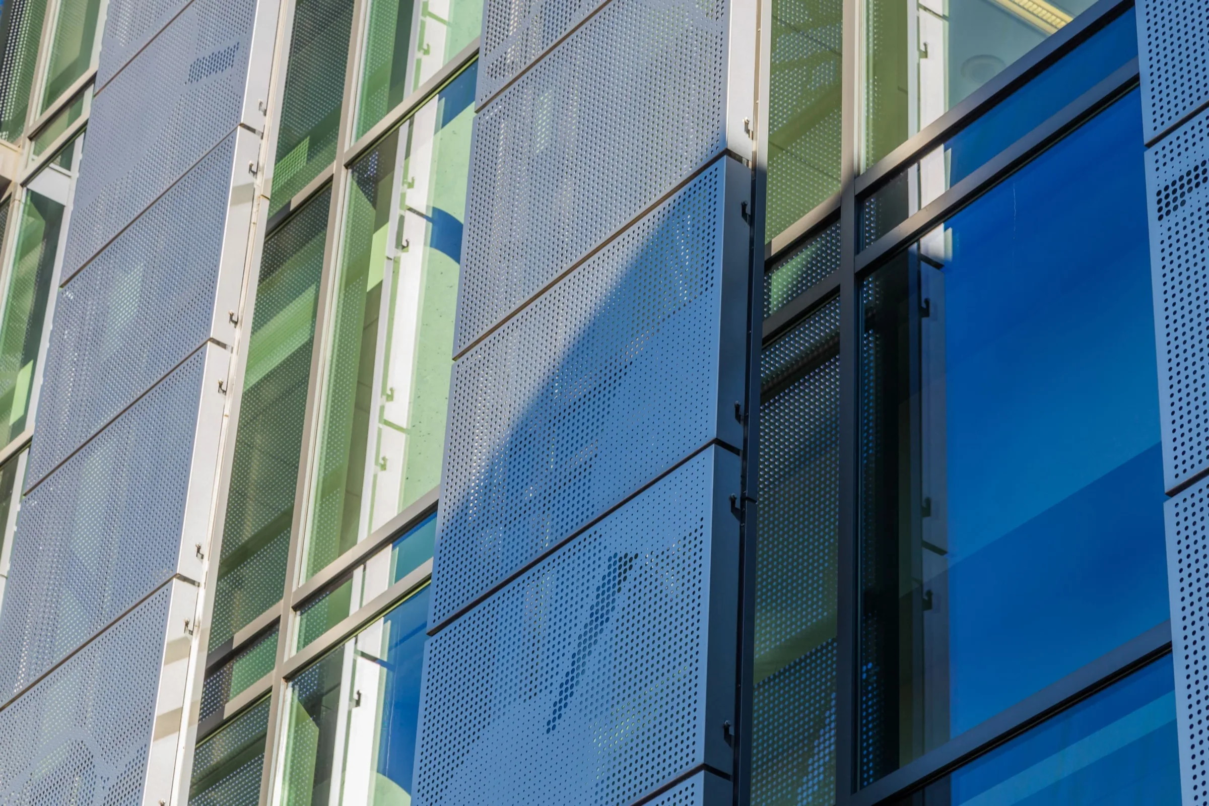 Perforated panels reflected in green glass
