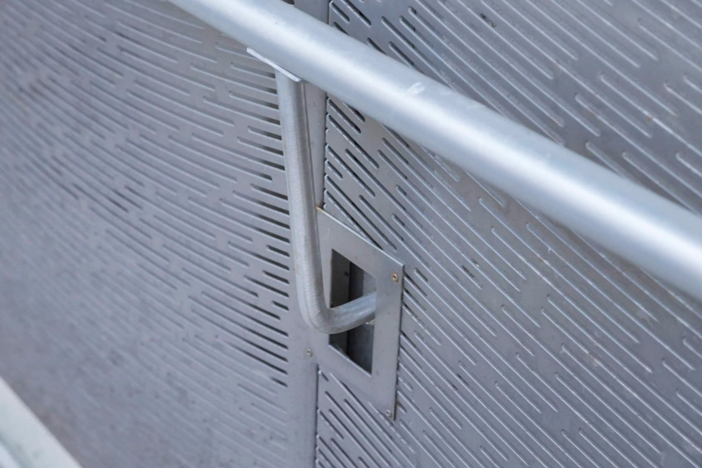 A handrail against a perforated panel, up close