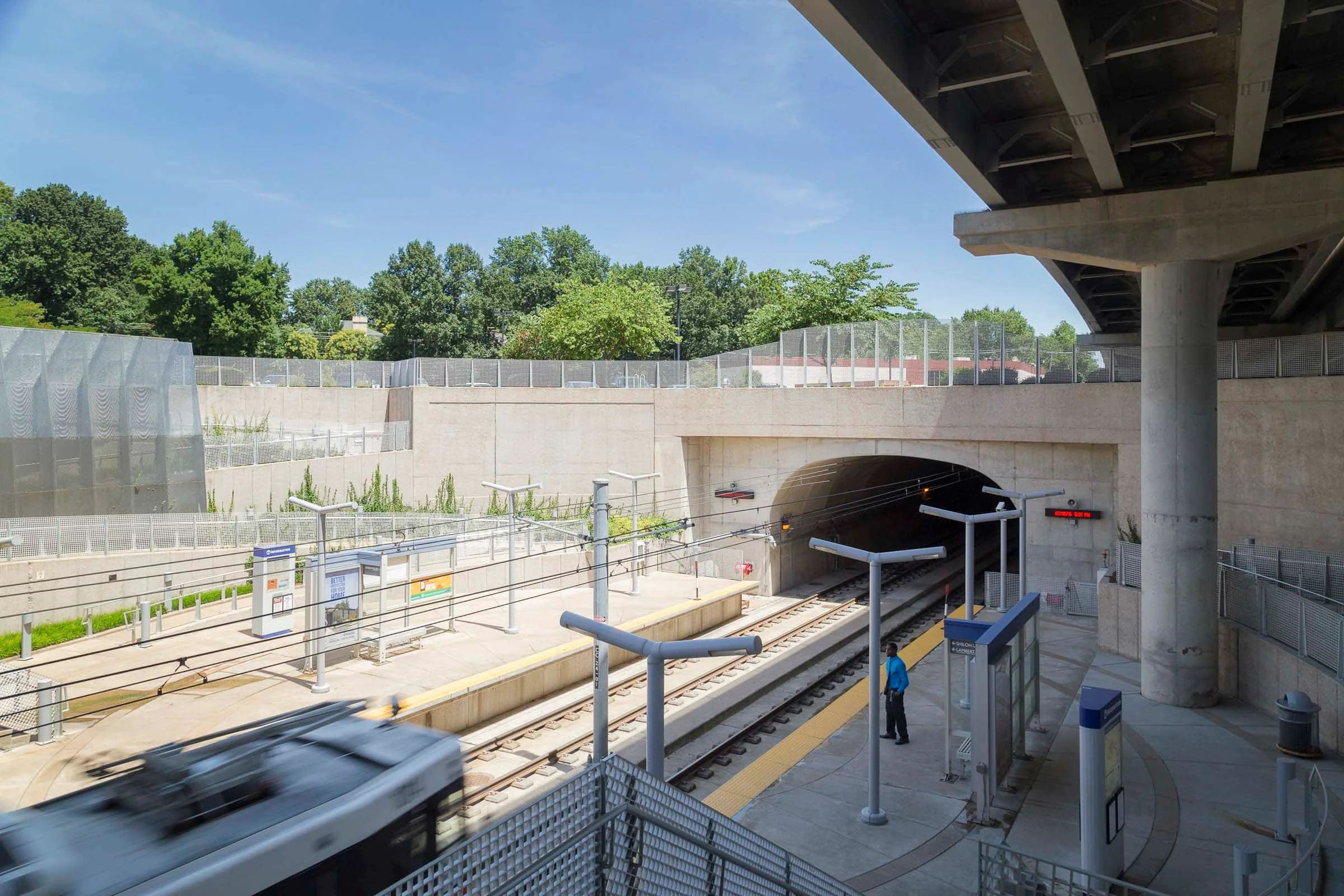 The platform and tunnel under an overpass, screens along the walls